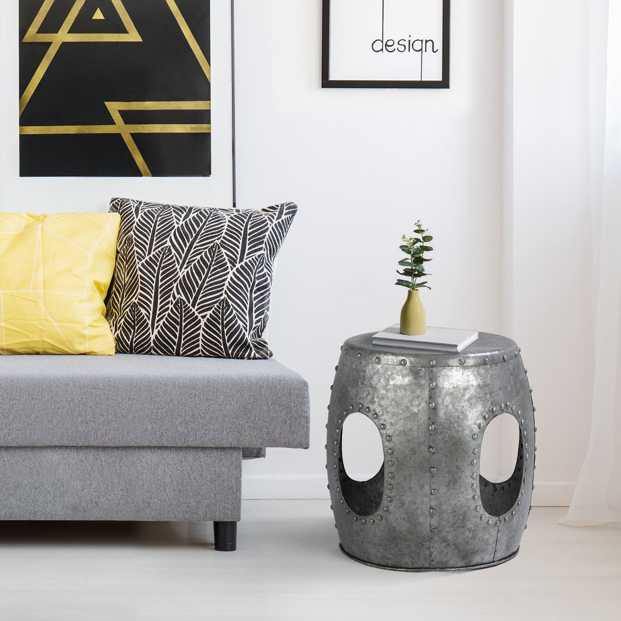 Graues Sofa mit Kissen und silbernem Beistelltisch in einem hellen Raum.