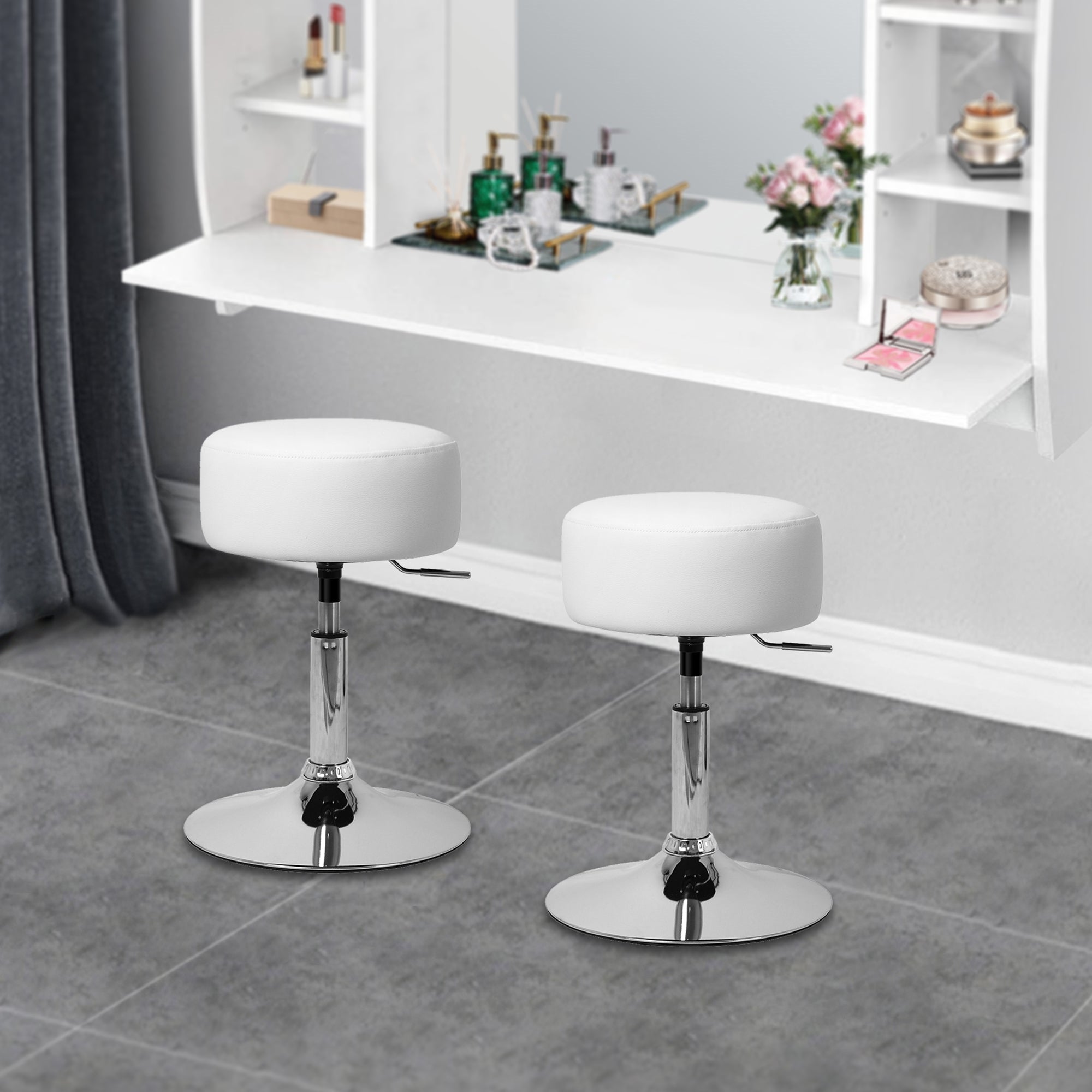 Deux tabourets blancs avec un siège rond devant un miroir et un support blanc.