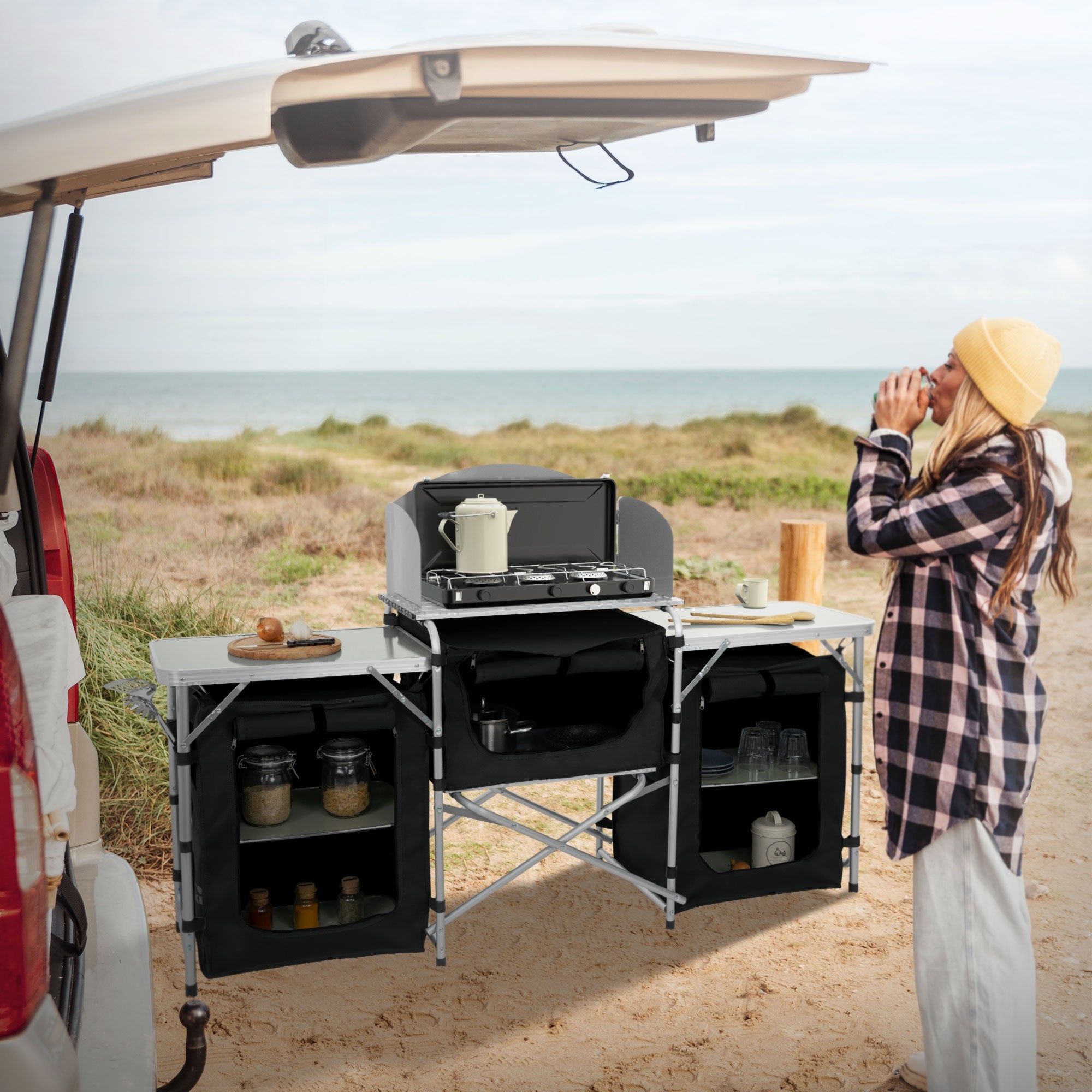 Femme en tenue à carreaux se tenant au coffre d'une voiture, cuisinant en plein air.