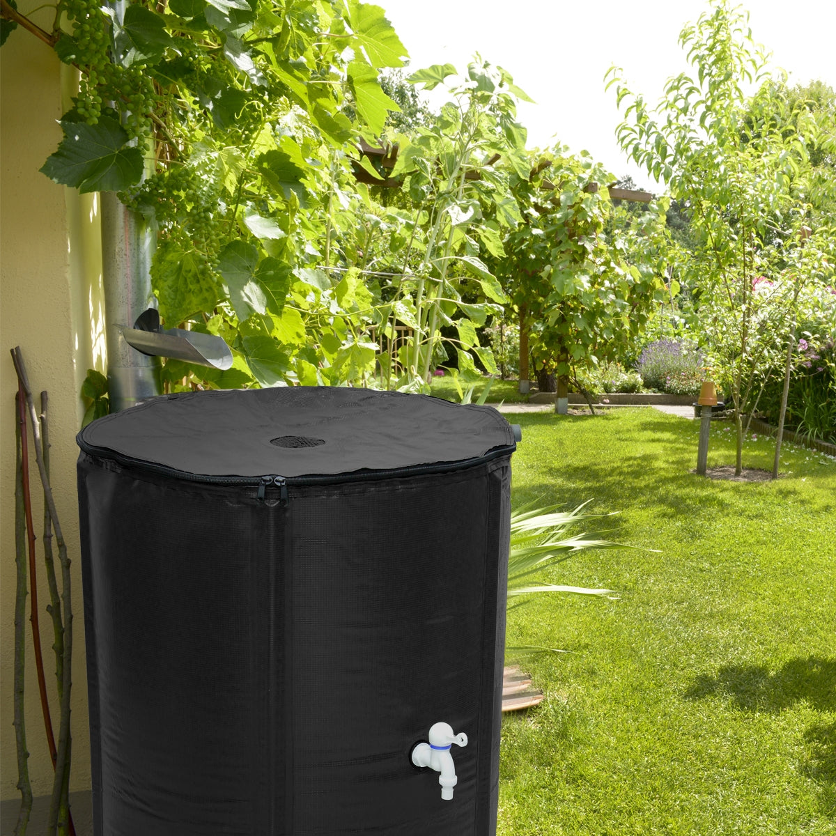 Tanque de agua negro en el jardín, rodeado de plantas y árboles.