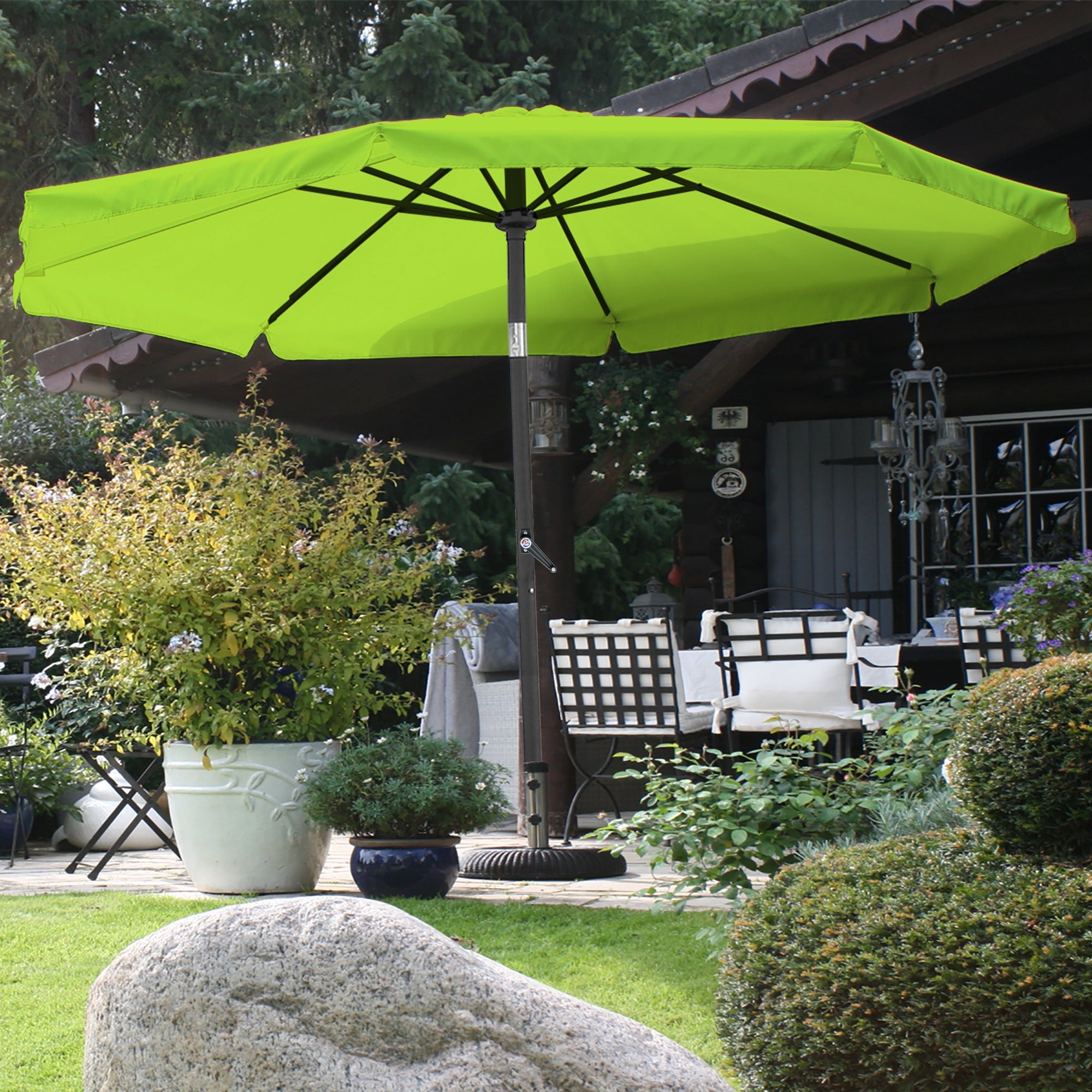 Grüner Sonnenschirm auf einer Terrasse mit Pflanzen und Möbeln.