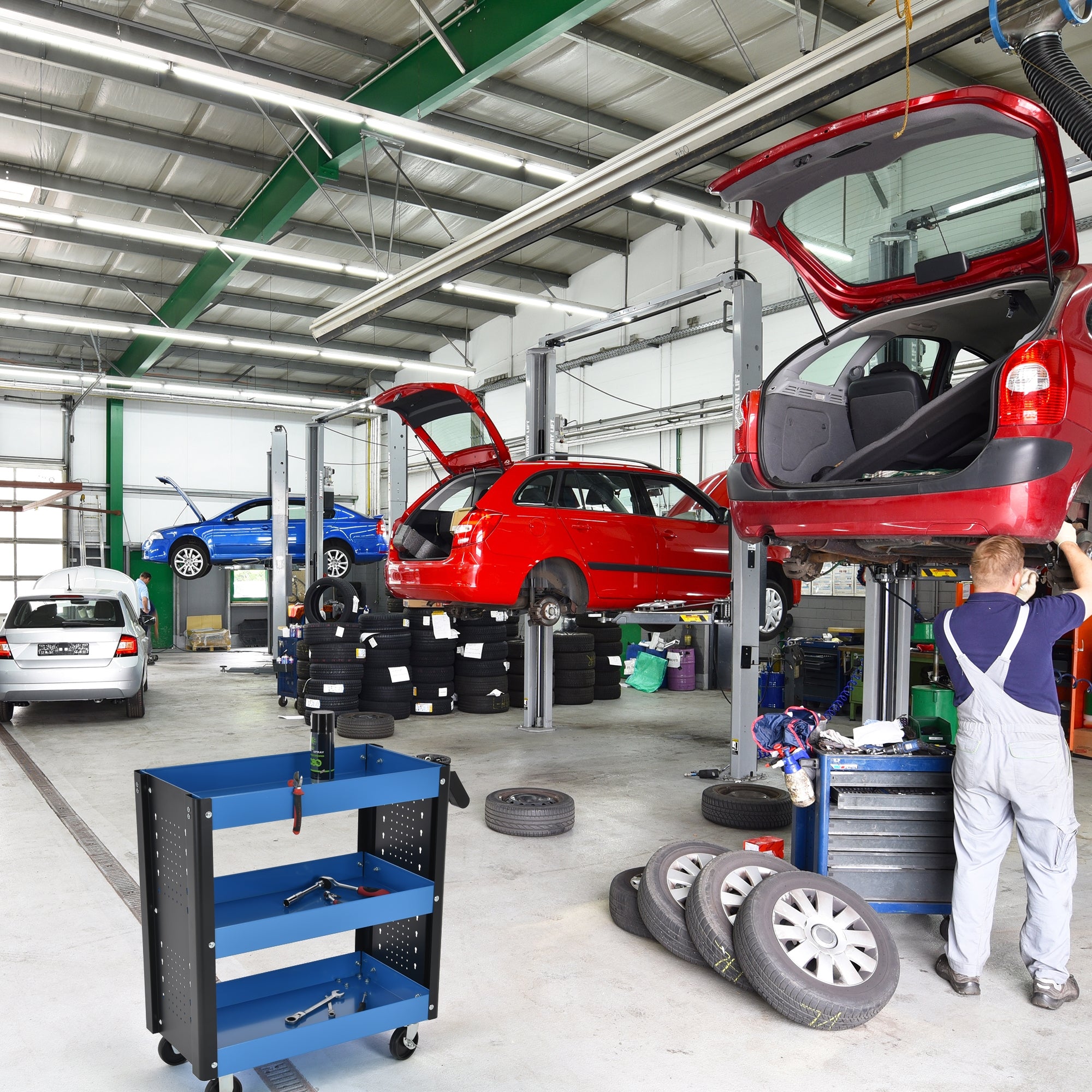 Dílna s automobily na zvedácích a modrým dílenským vozíkem.