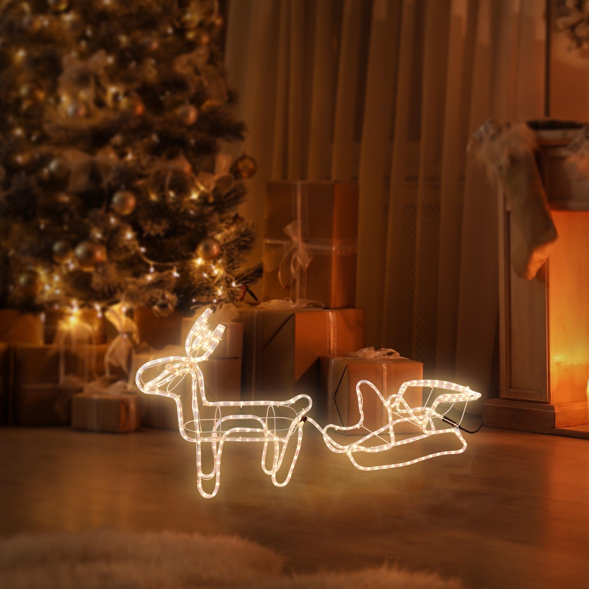 Leuchtendes Rentier und Schlitten vor einem Weihnachtsbaum.