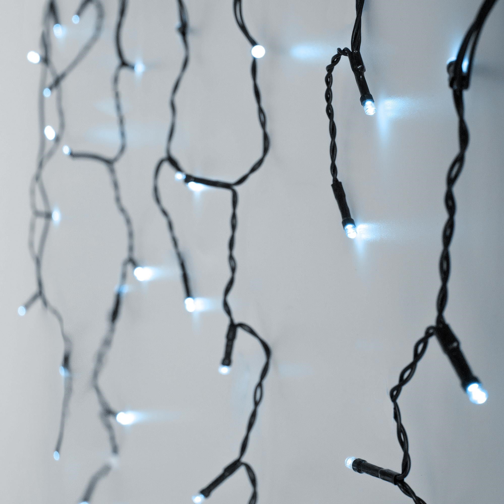 Schwarze Lichterkette mit blauen Lichtern an einer Wand.