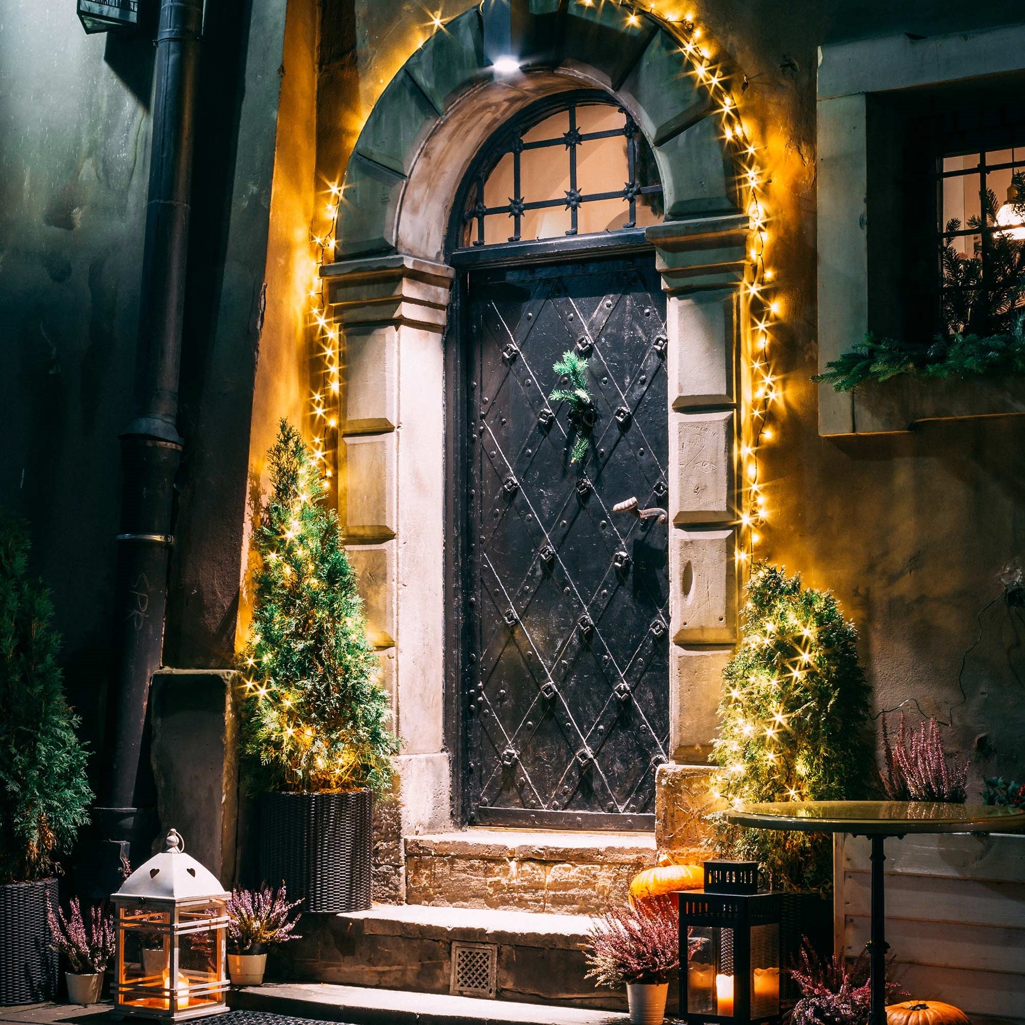 Una porta decorata festosamente con luci e piante.