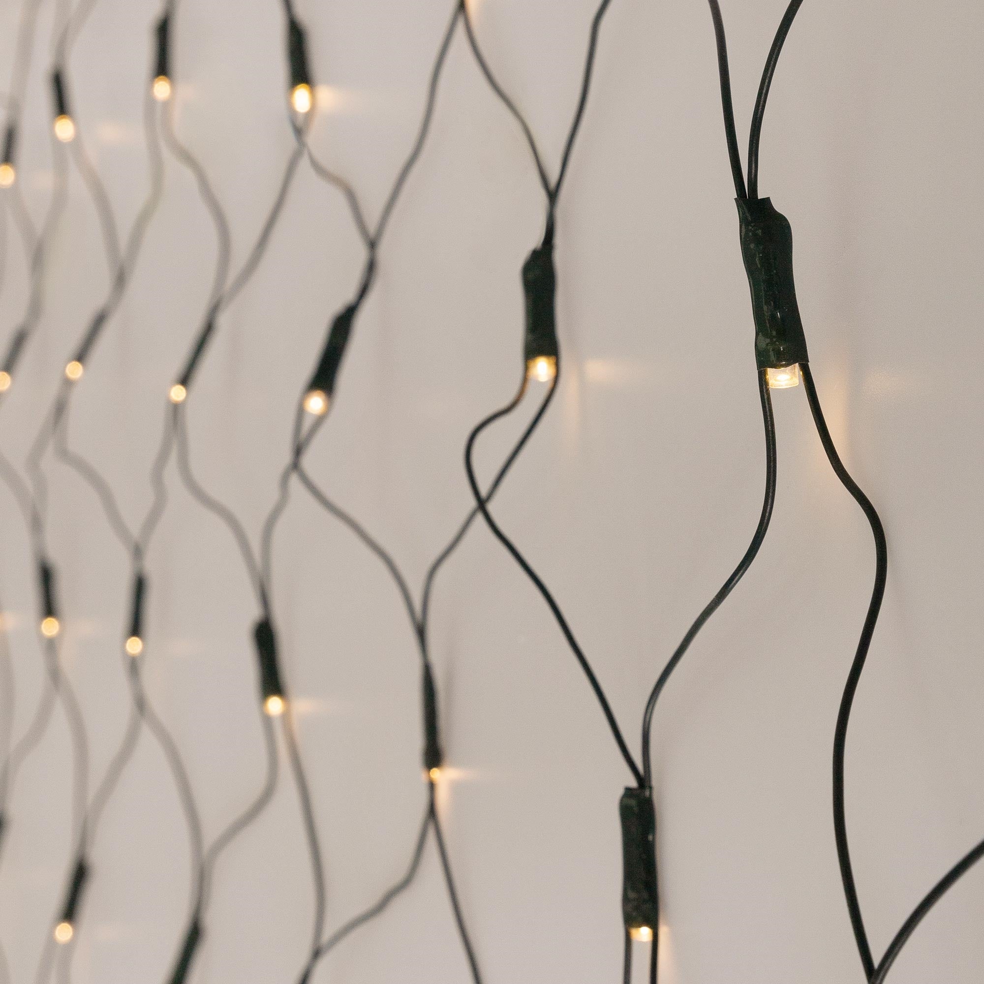 Vánoční osvětlení s teplými bílými LED na světlém pozadí, kabel viditelný.