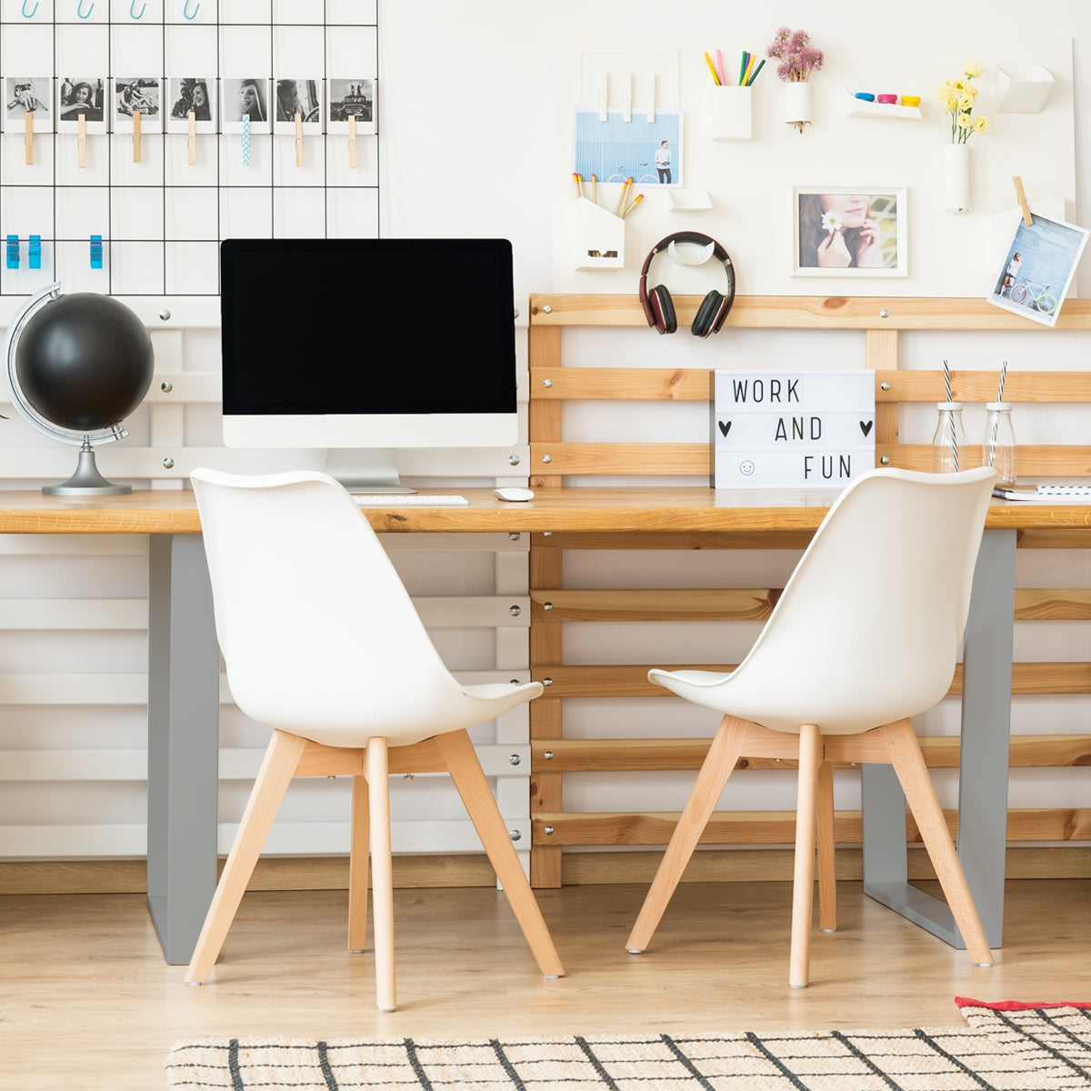 Ein Schreibtisch mit Computer, zwei Stühlen und Dekoration an der Wand.