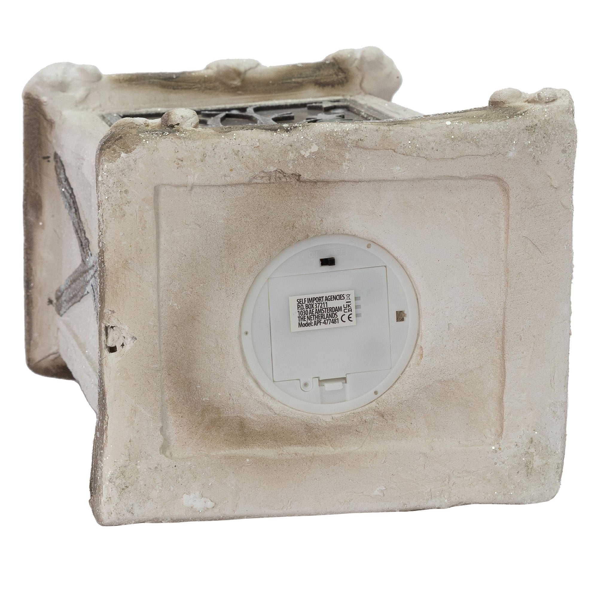 Bagsiden af et hvidt, kvadratisk objekt med en rund batteridæksel.