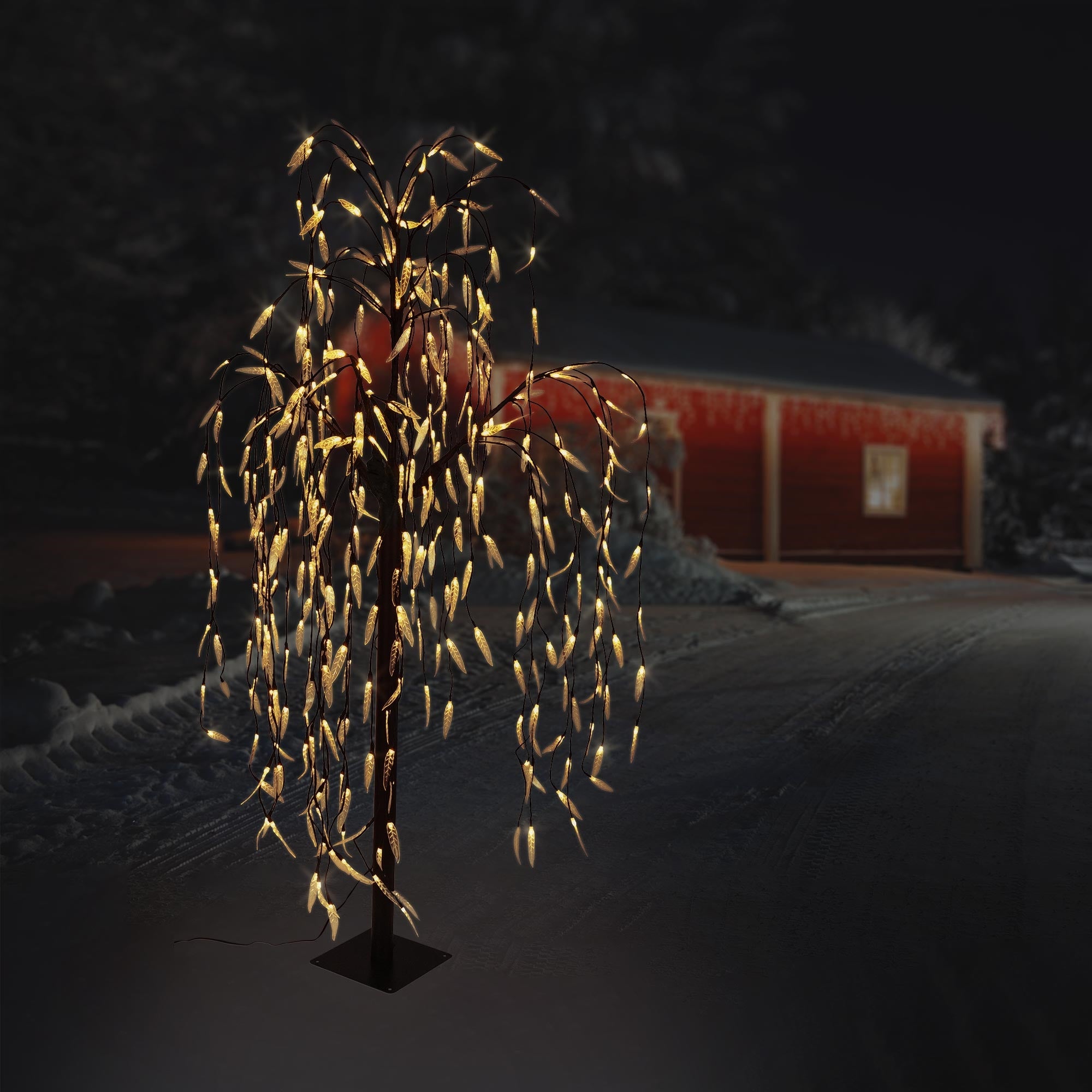 Árbol iluminado en la nieve por la noche, con luces cálidas.