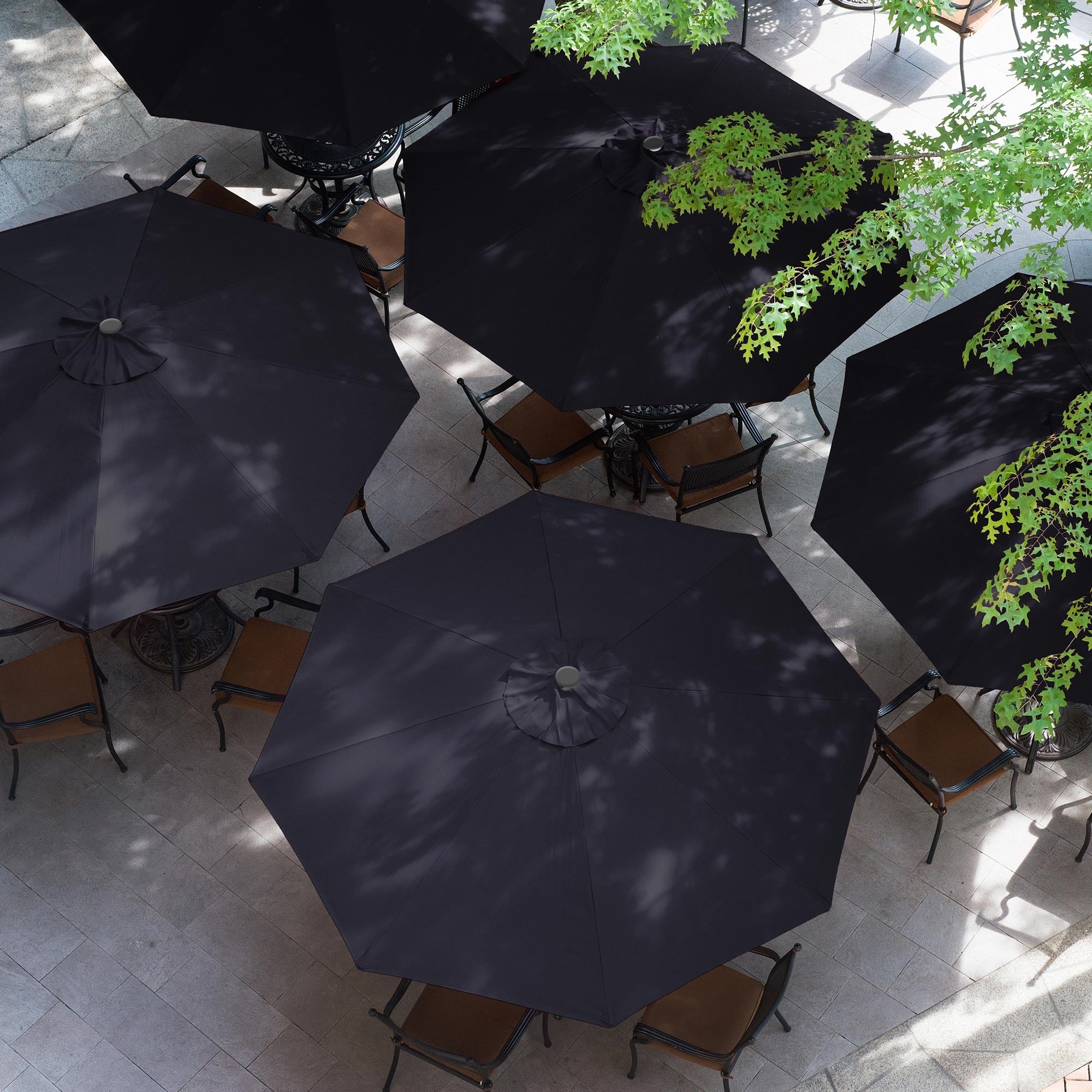 Vue aérienne de plusieurs parasols noirs et chaises sur une place.