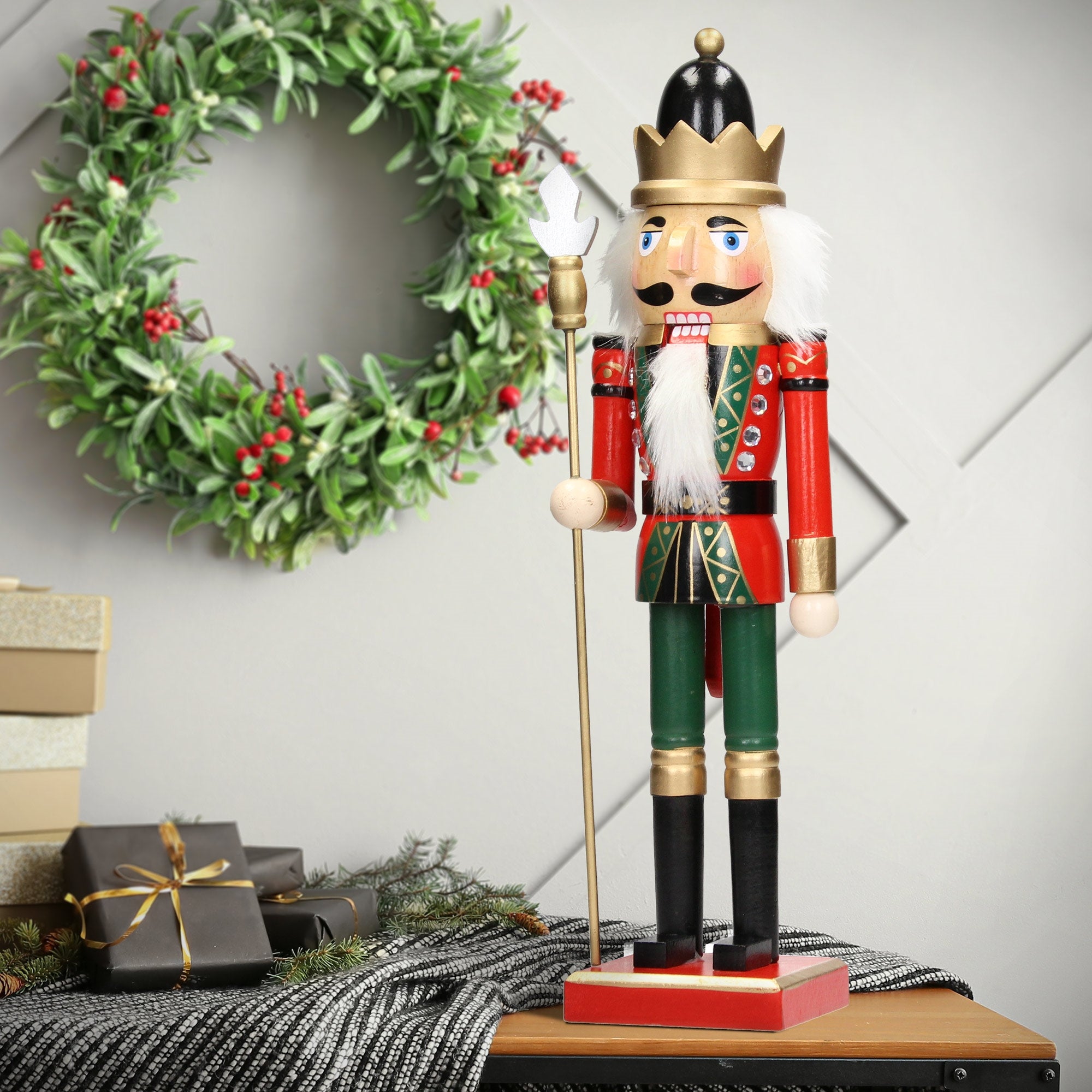 Nussknacker mit Krone, steht vor einem Weihnachtskranz.