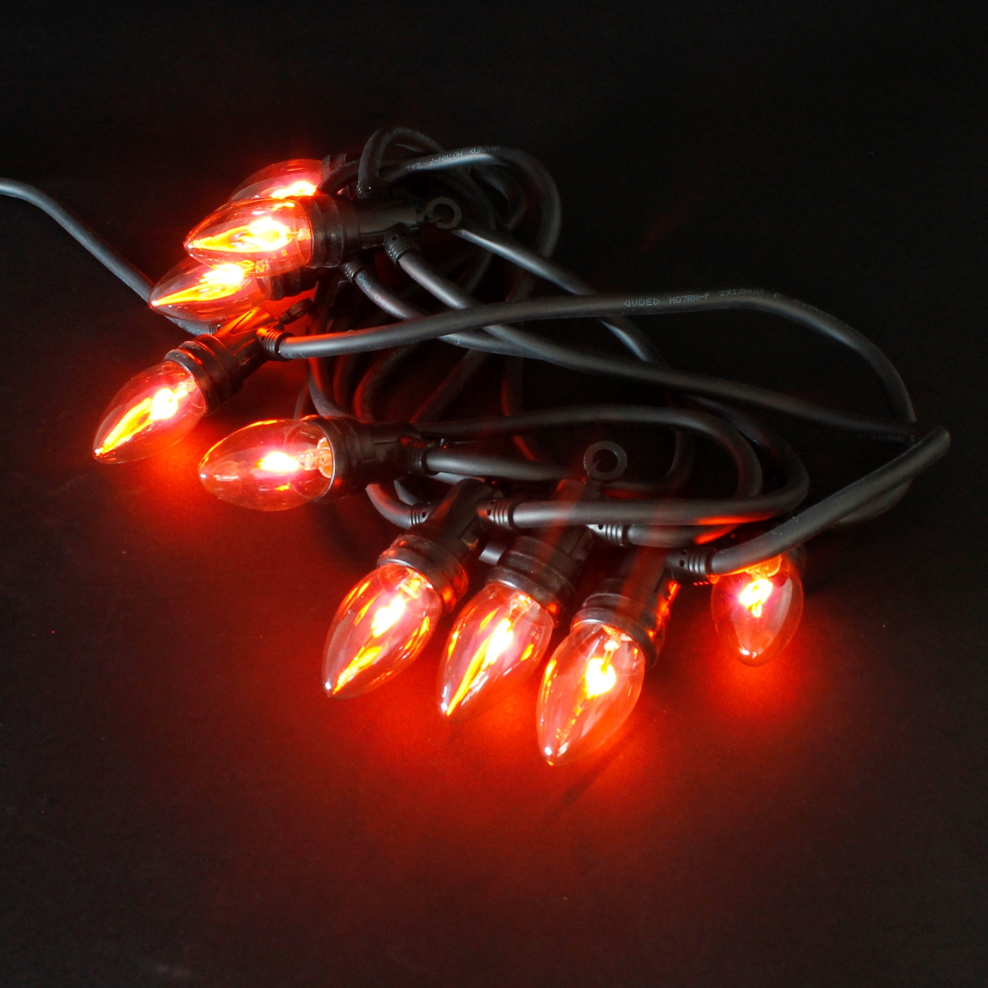 String of lights with orange lamps on a black background.