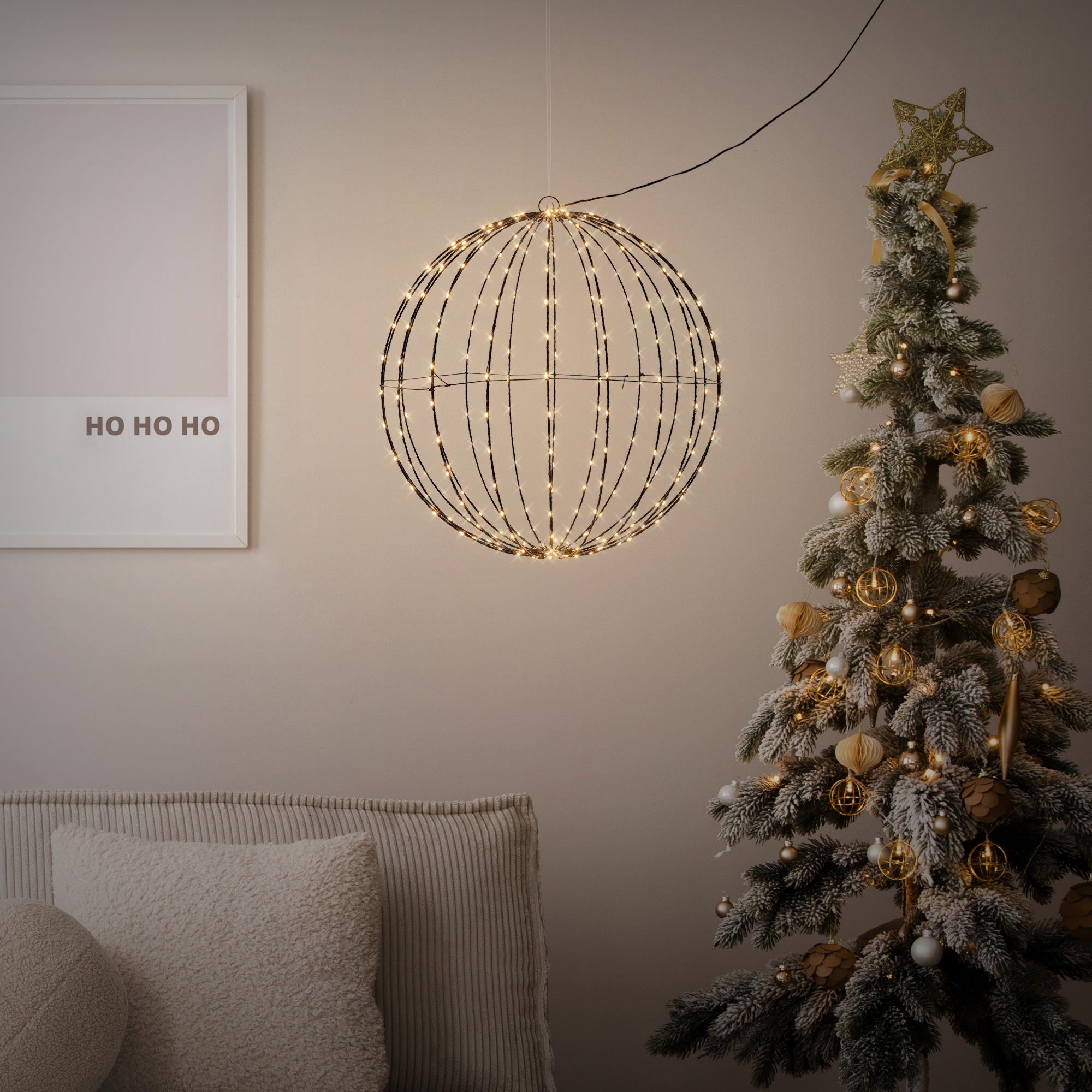 En rund, belyst dekoration hænger over et juletræ.