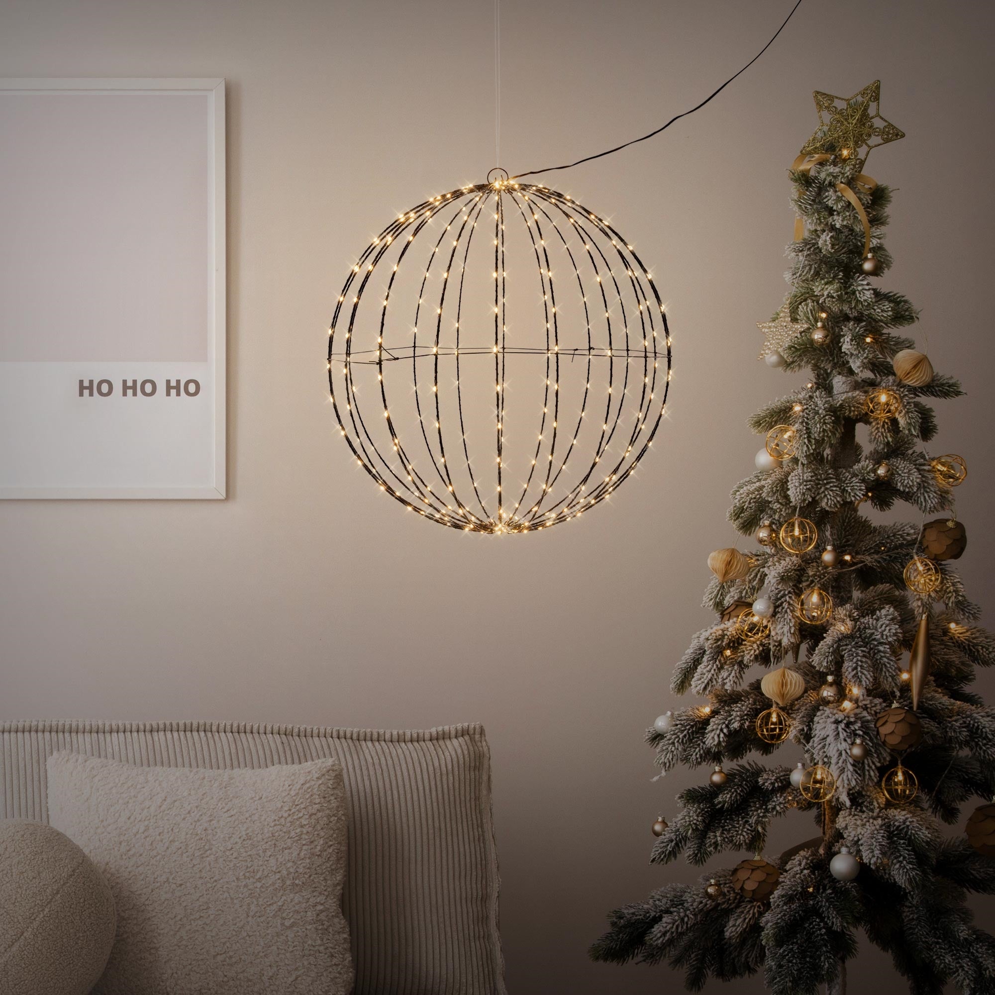 Una decoración redonda iluminada cuelga sobre un árbol de Navidad.