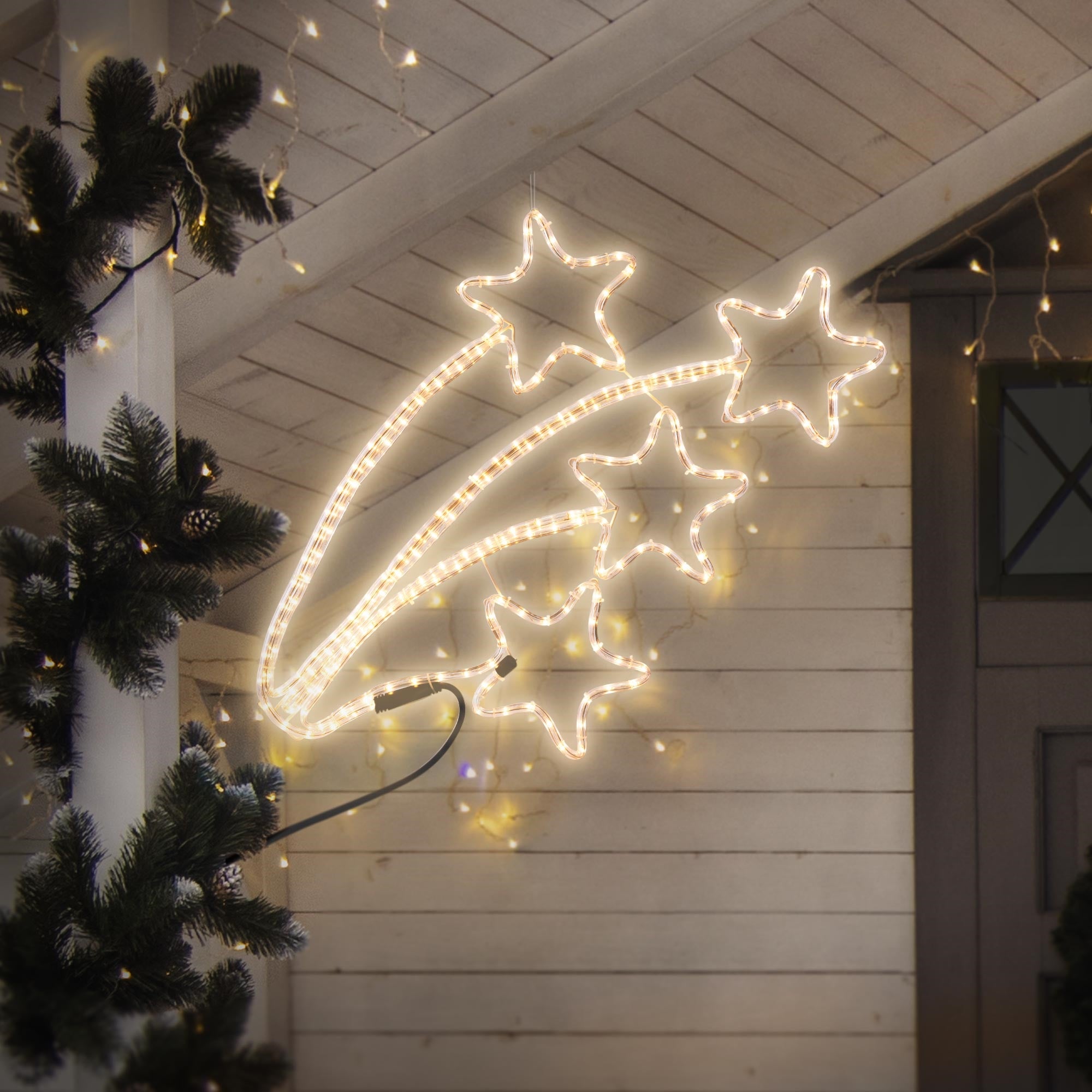 Cadena de luces en forma de estrella iluminada en una pared con decoración navideña.