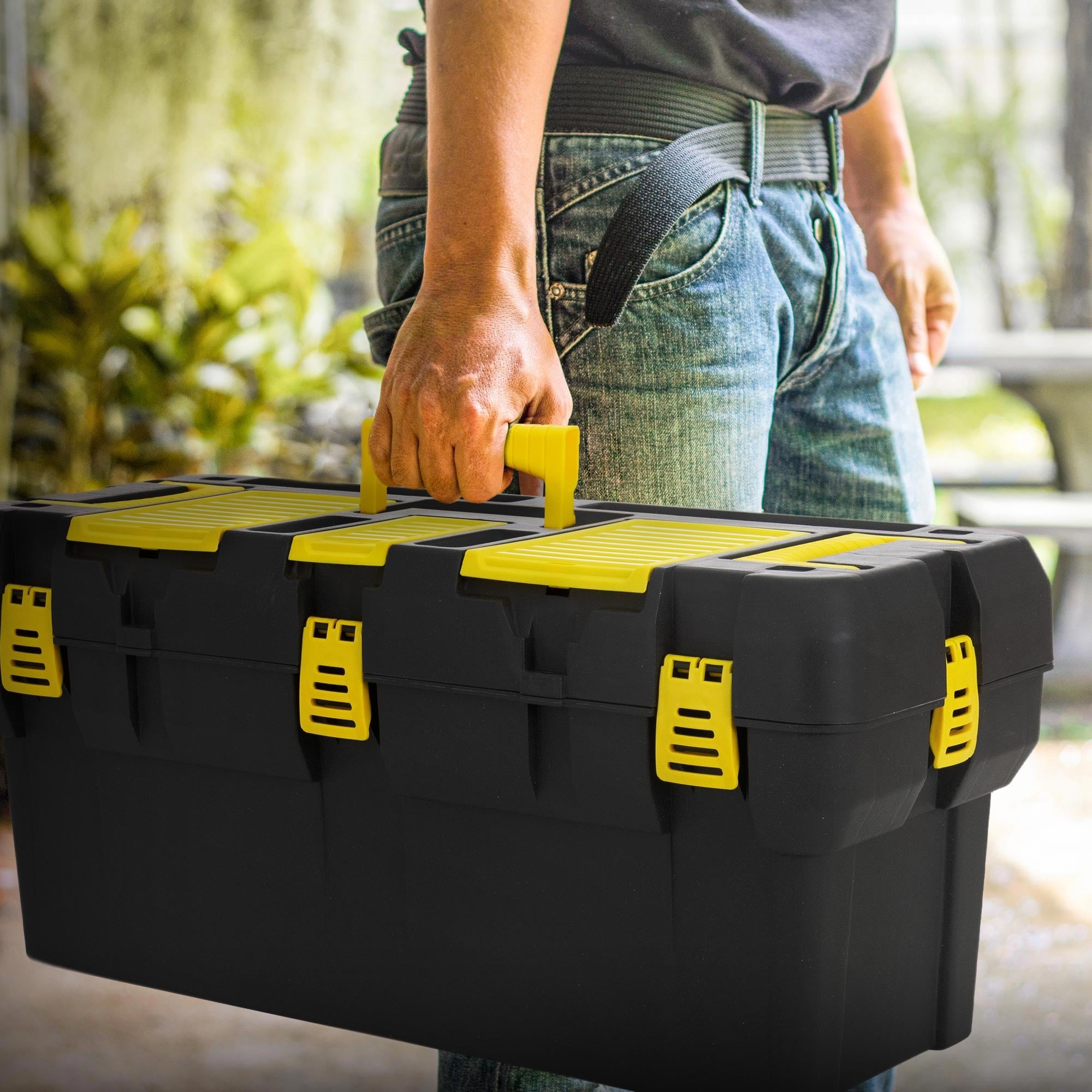 Person carrying a black toolbox with yellow fasteners.