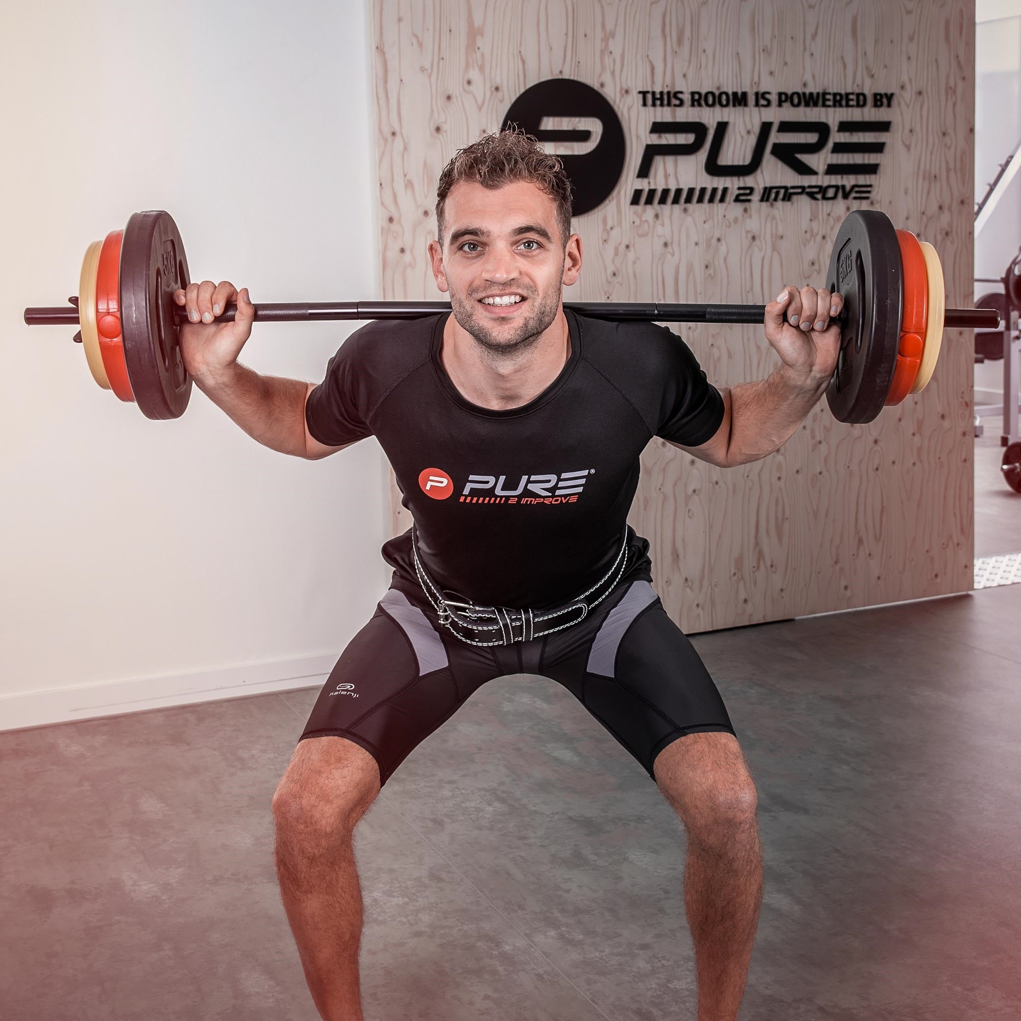 Ein Mann führt eine Kniebeuge mit Gewichten in einem Fitnessstudio aus.