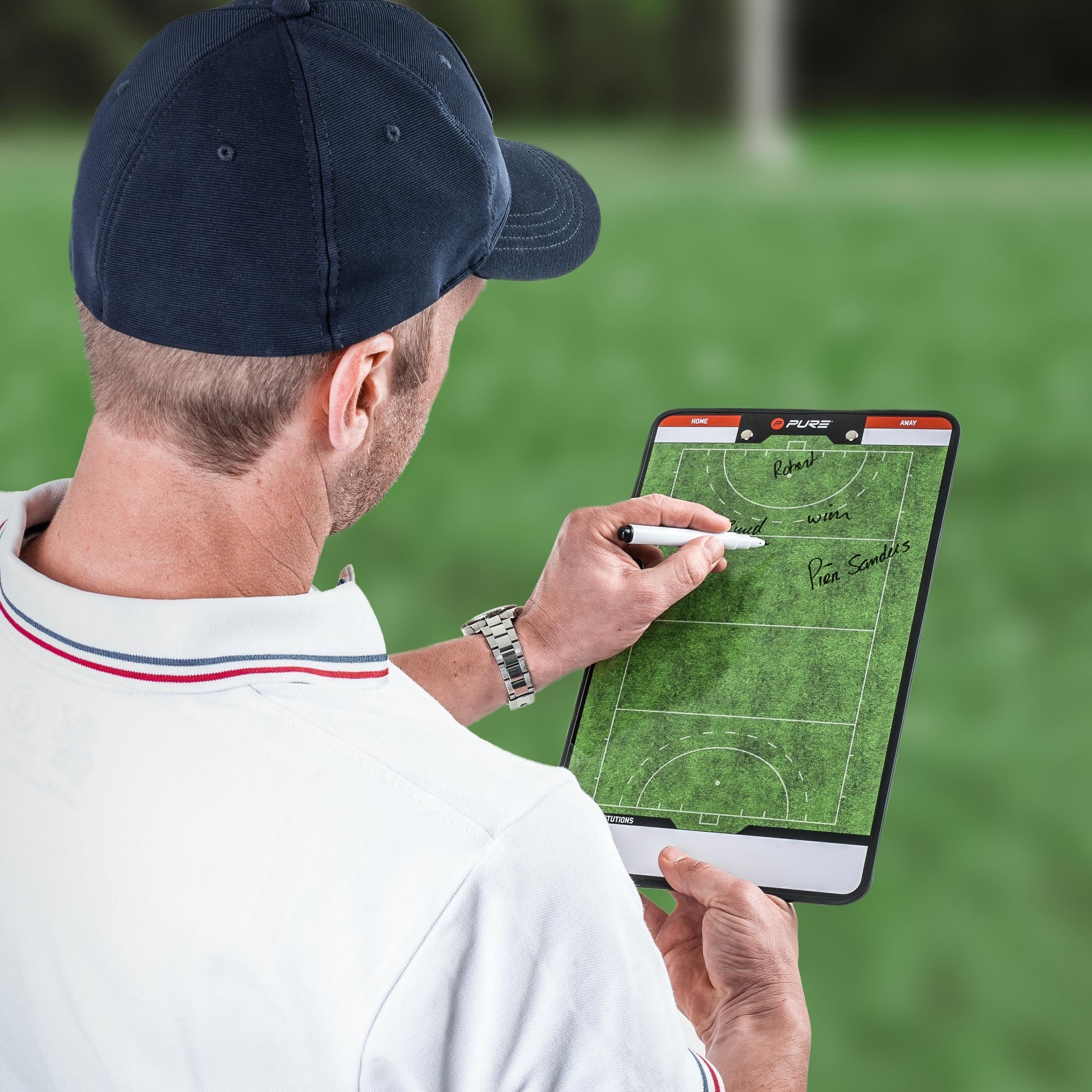 Entrenador escribe en una pizarra táctica al aire libre.