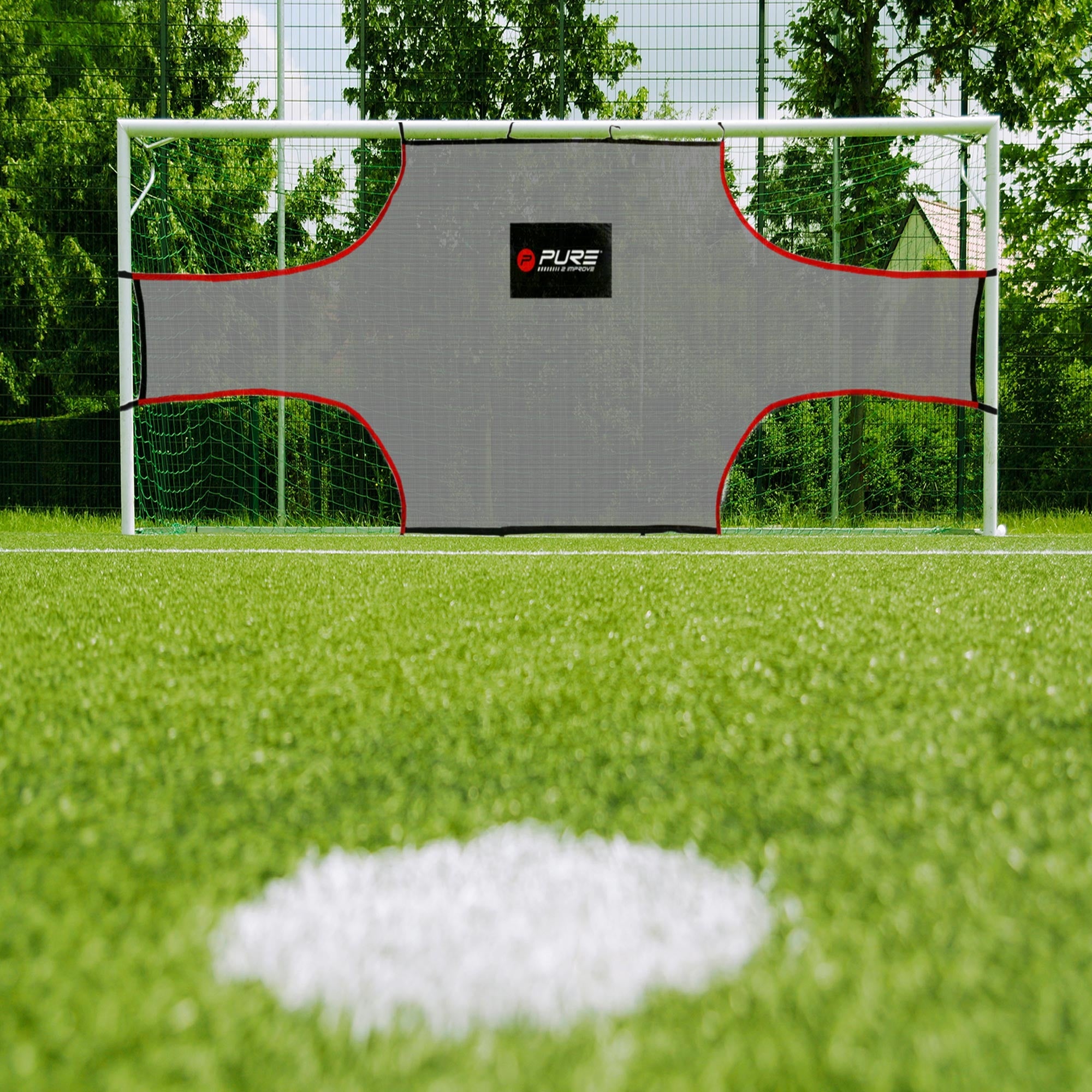 Fußballtor mit einem grauen Netz und rotem Rand auf einem Rasenplatz.