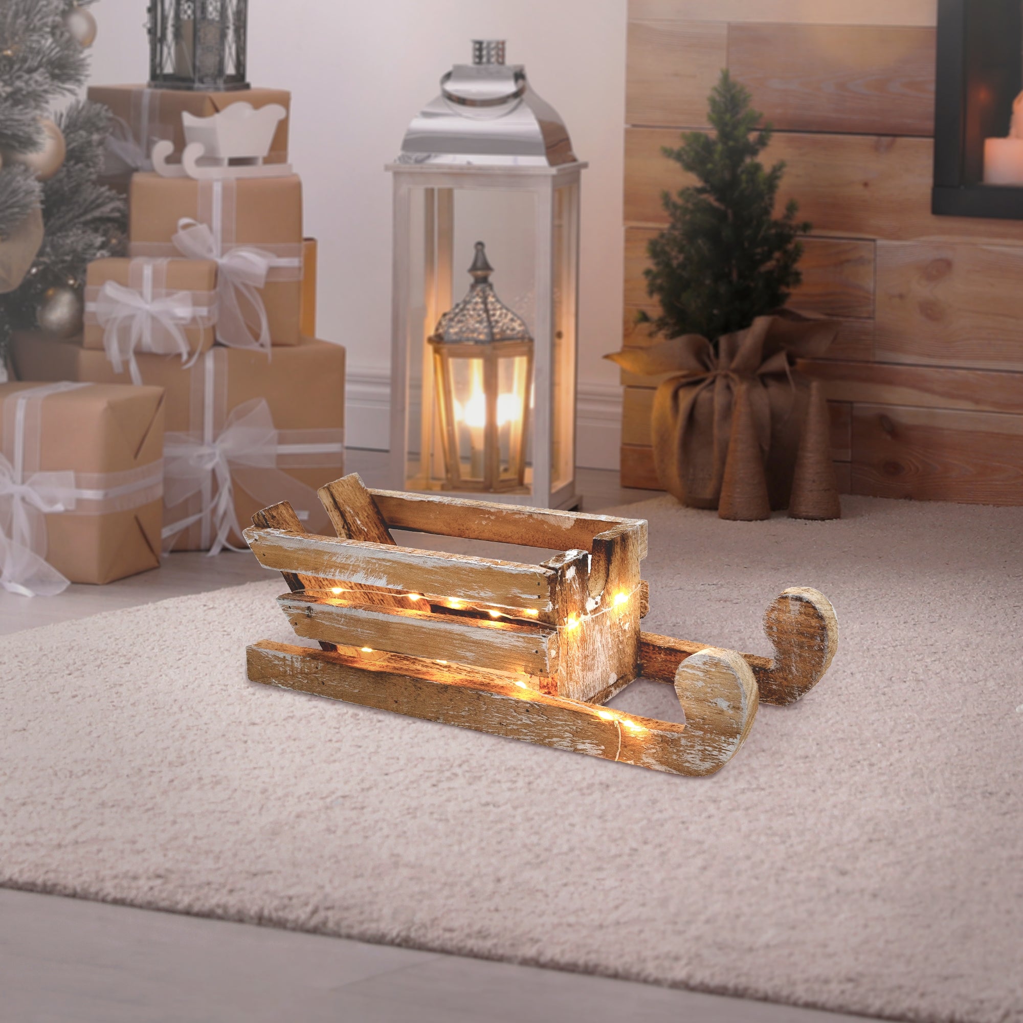 Holzschlitten mit Lichtern, auf Teppich, neben Laterne und Tannenbaum.
