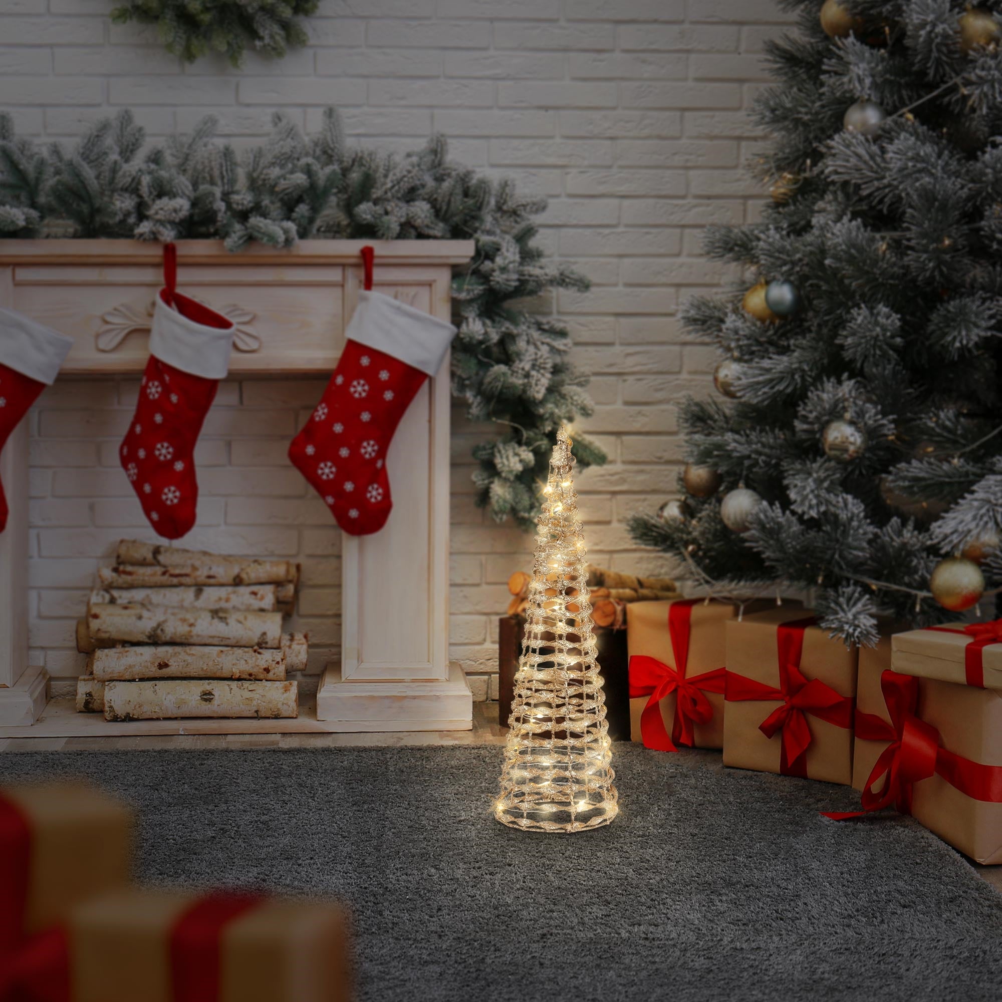 En oplyst dekorationstræ ved en pejs med julestrømper.