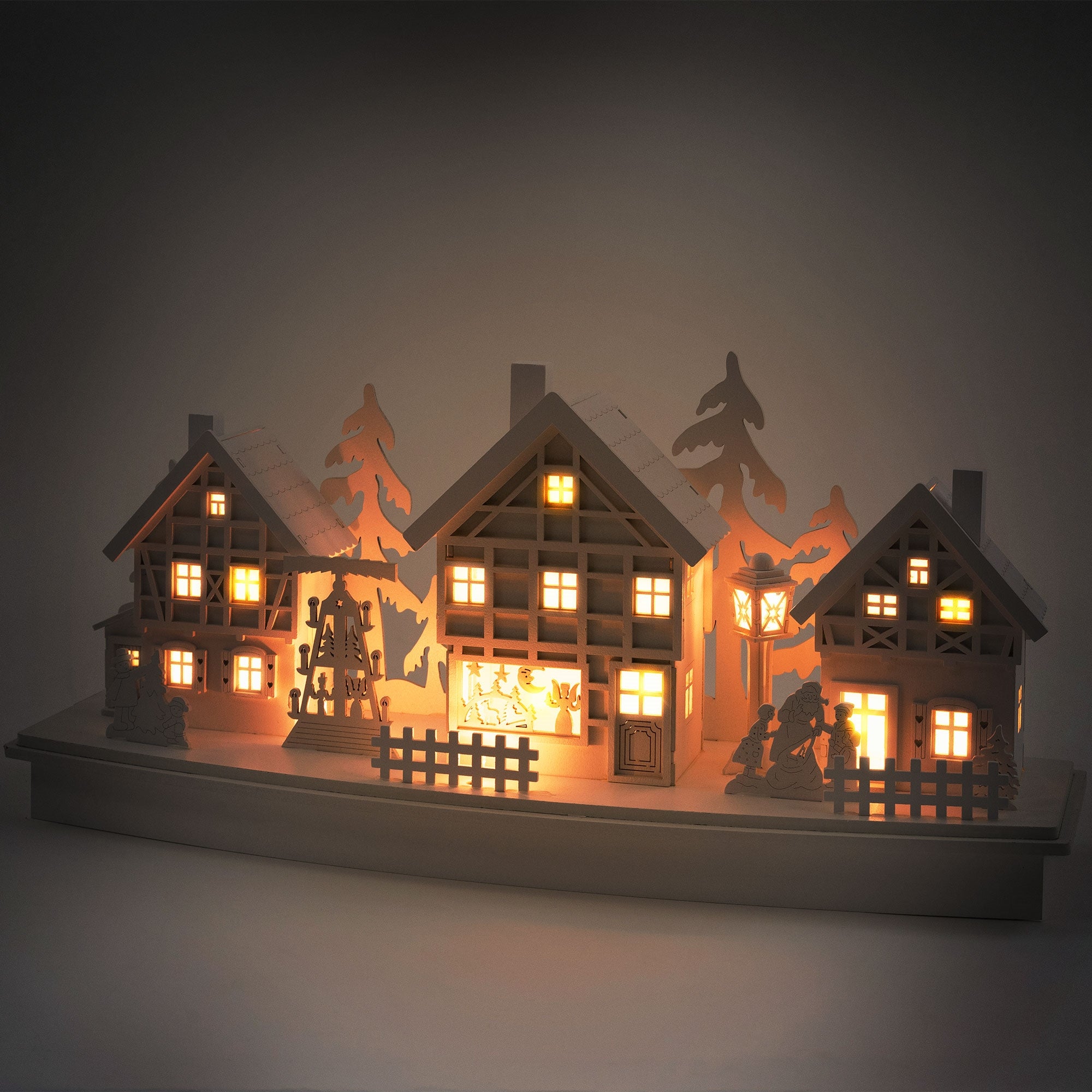 Verlichte houten decoratie met meerdere huizen en bomen.