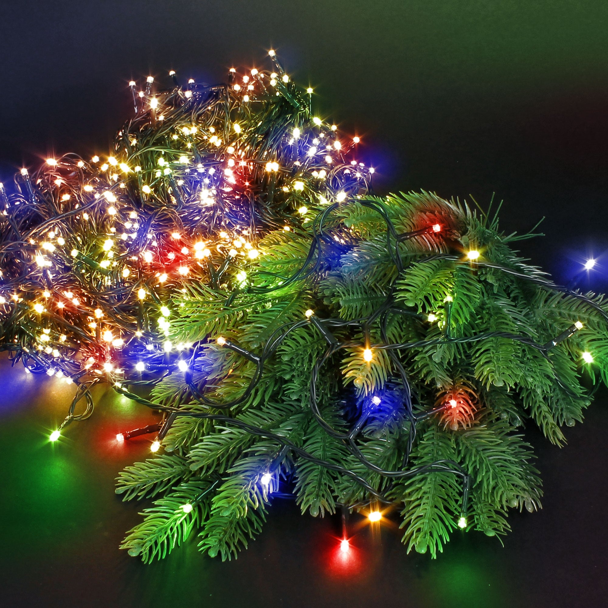 String lights with colorful lights and pine branches on a black background.