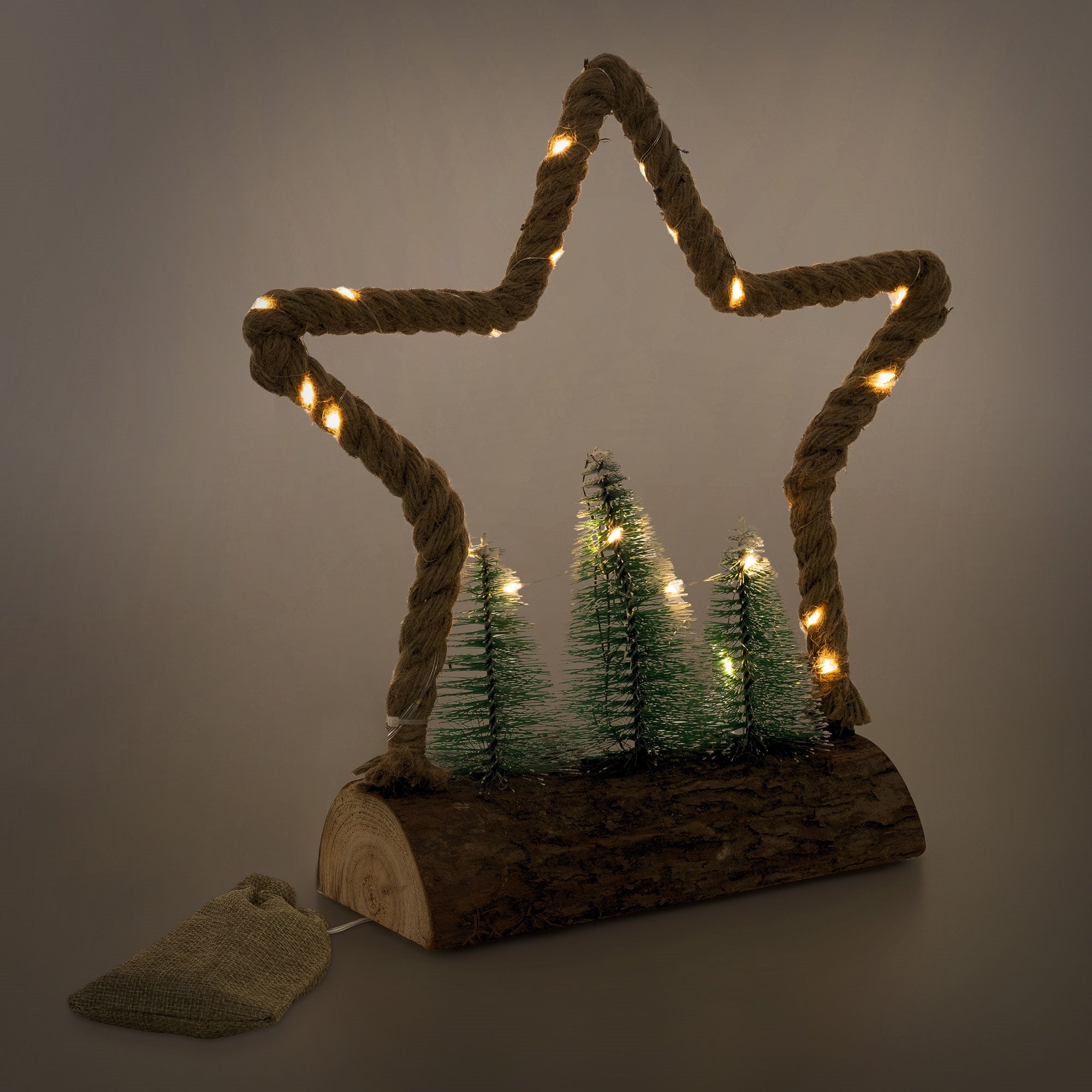 Tre alberi di abete in una cornice di legno a forma di stella con luci al buio.