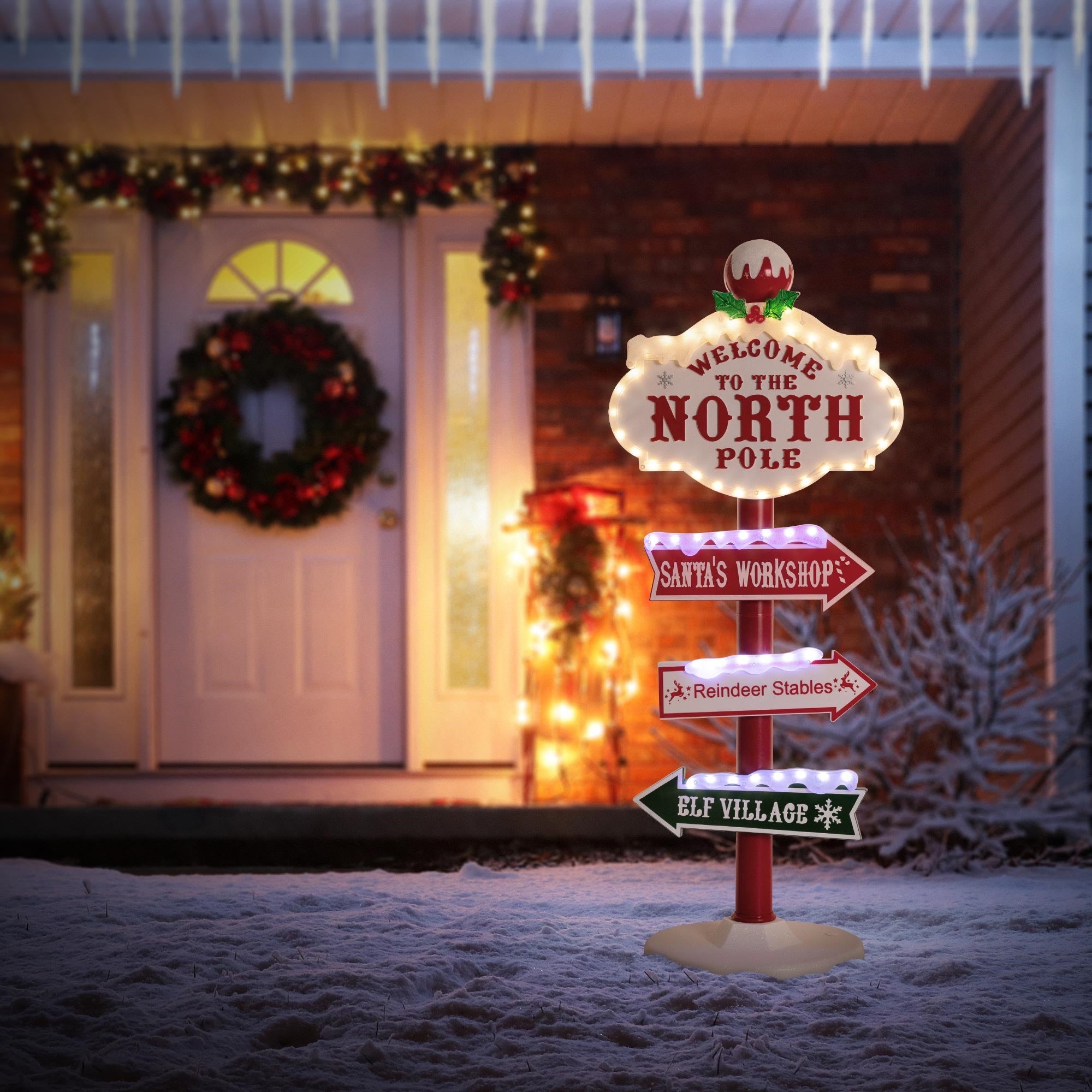 Beleuchtetes Schild mit 'Welcome to the North Pole' und Richtungspfeilen.