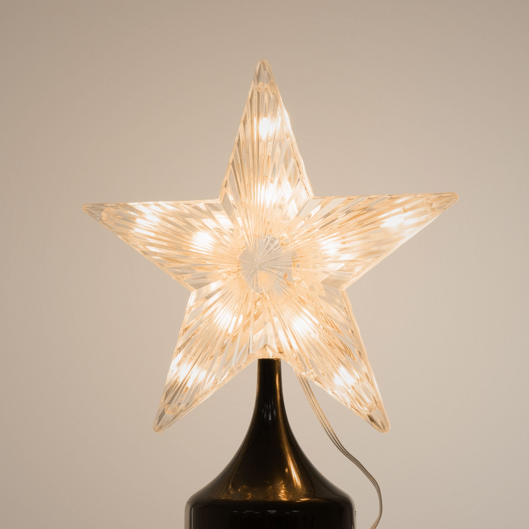 Transparent, illuminated star on a black base.