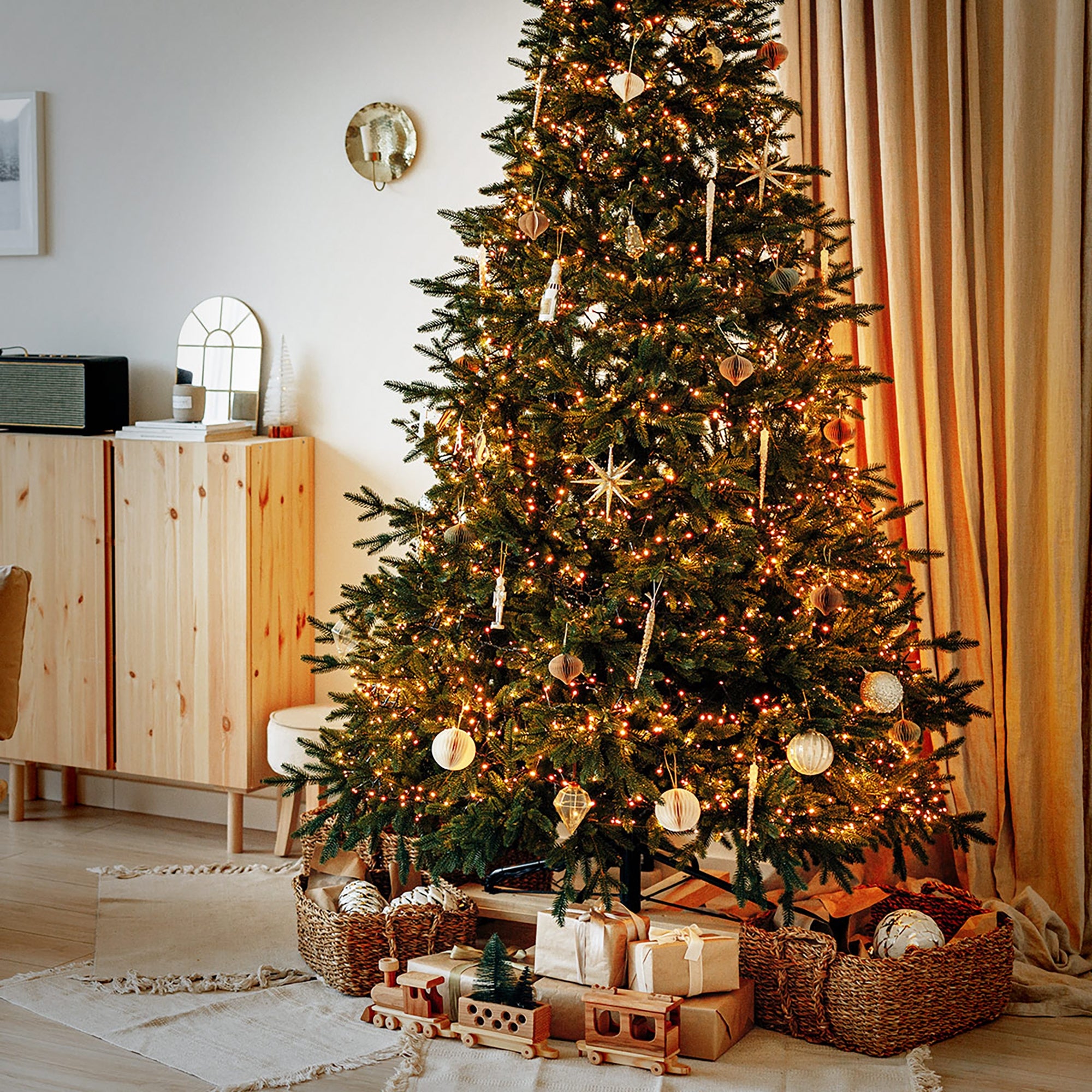 Egy díszített karácsonyfa fényekkel és ajándékokkal alatta.