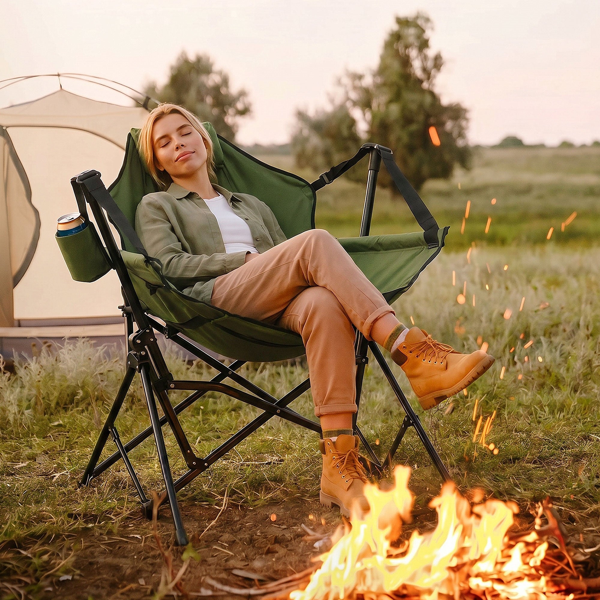 Frau sitzt entspannt in einem grünen Campingstuhl neben einem Lagerfeuer.