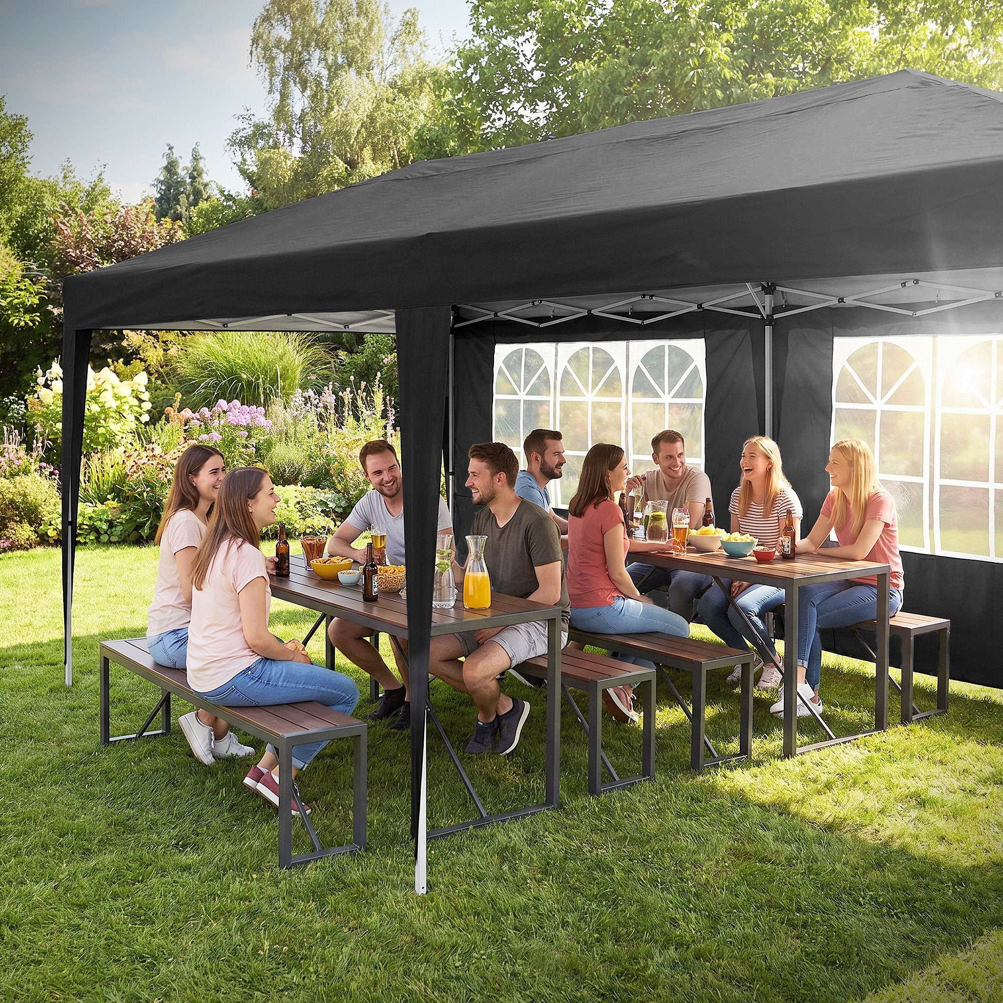Gruppe von Menschen sitzt an einem Tisch unter einem Pavillon im Garten.