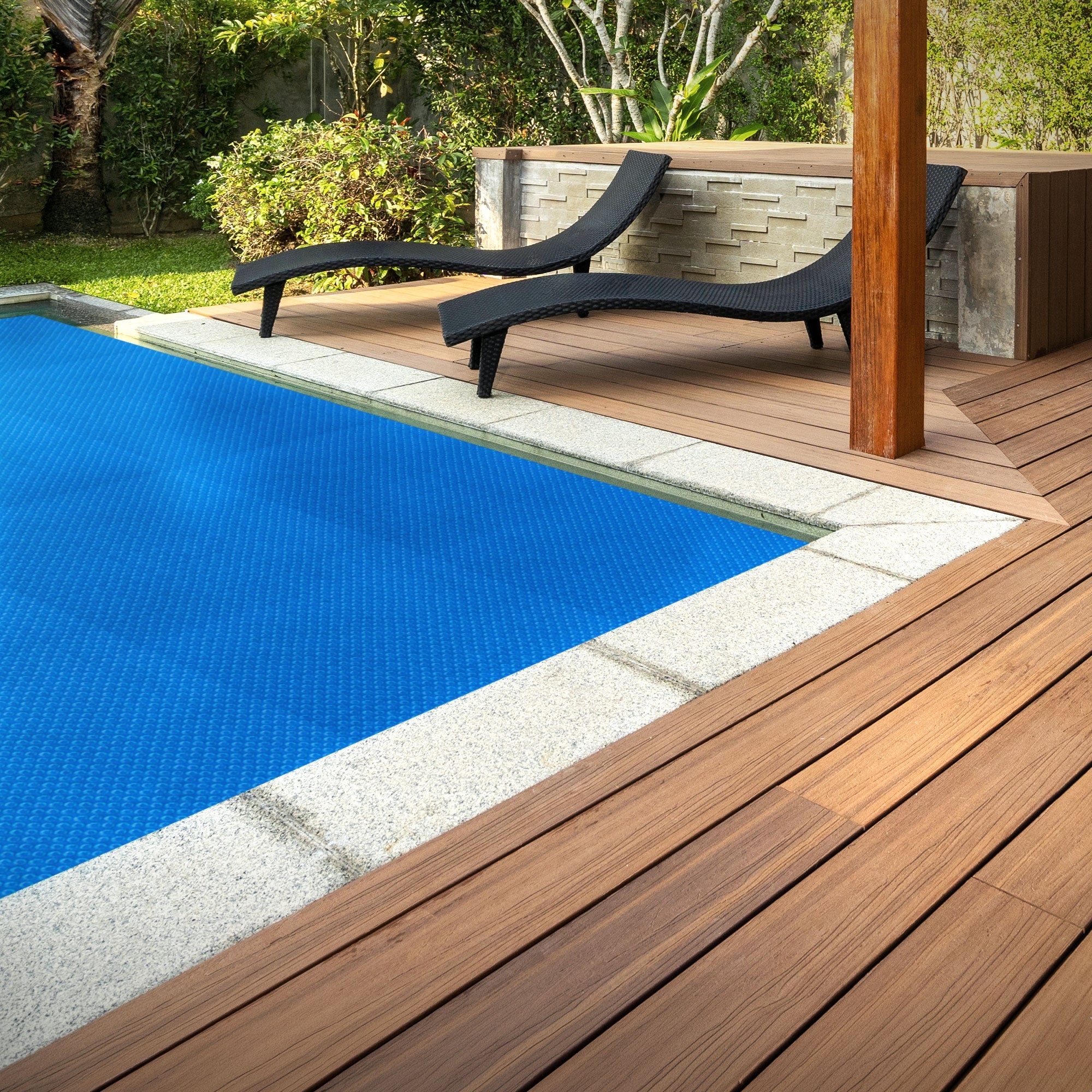 Zwei Liegen neben einem blauen Pool auf einer Holzterrasse.