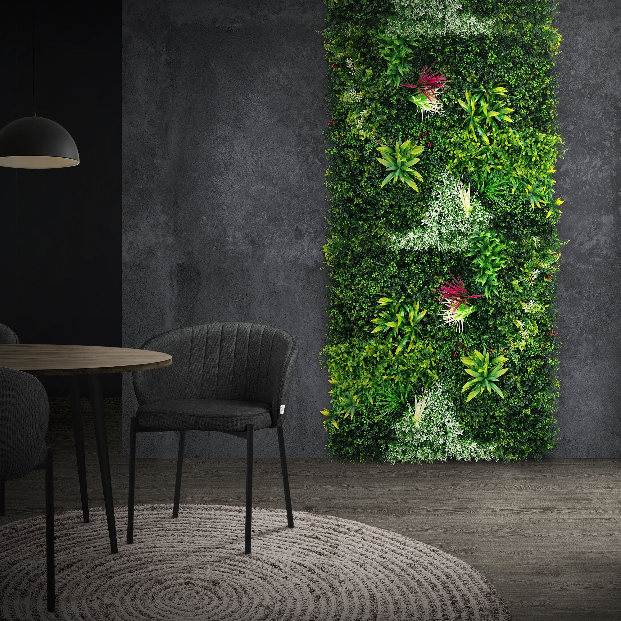 Espace avec un mur de plantes haut, une table et un tapis rond.