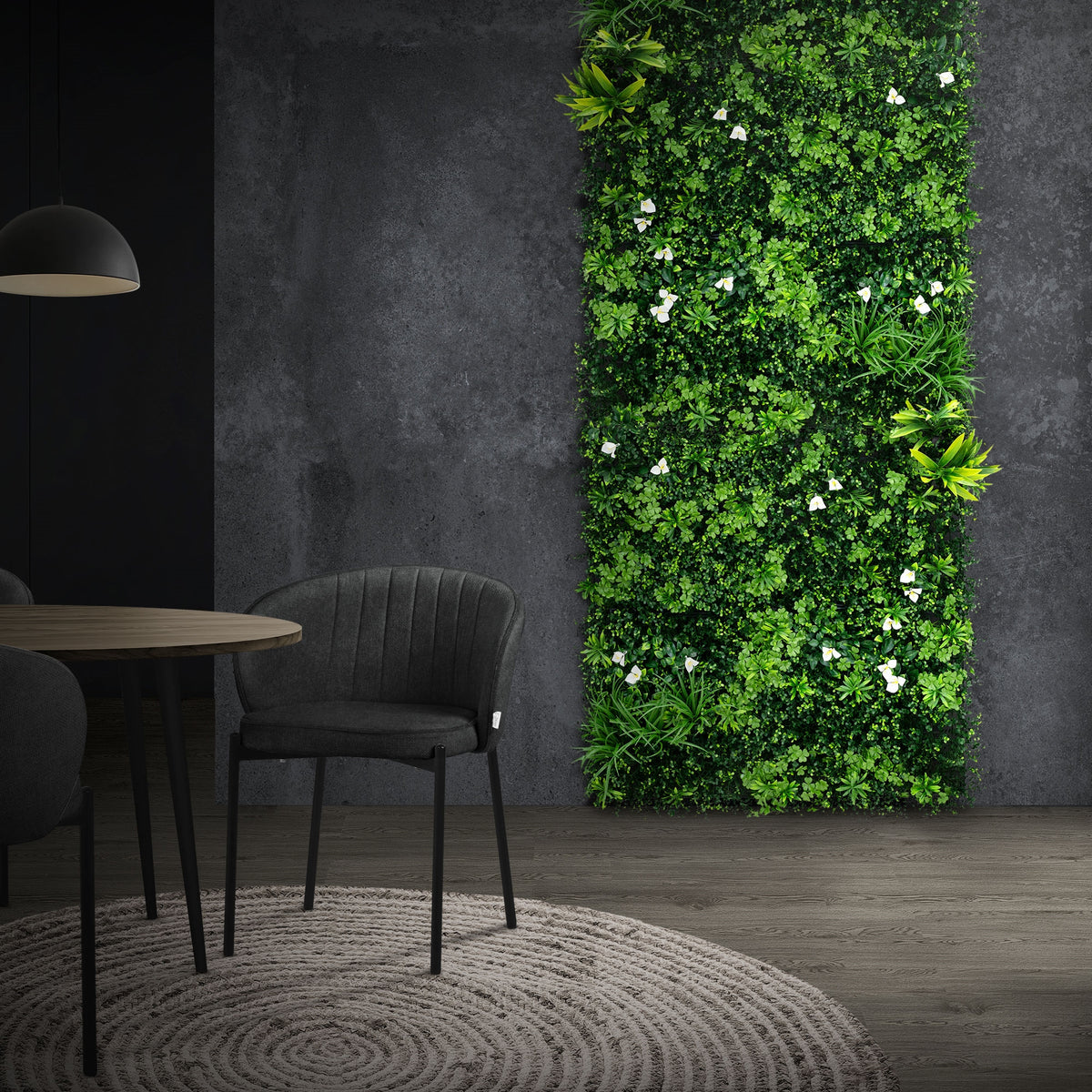 Espace avec un mur de plantes vertes, un tapis rond et une table avec des chaises.