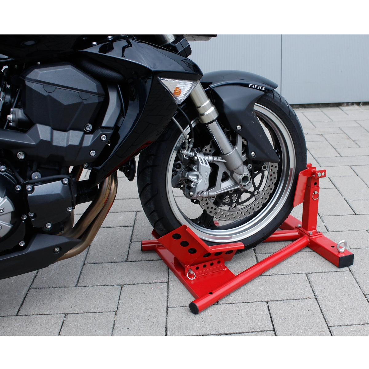Un support de moto rouge qui soutient une moto avec un cadre noir.