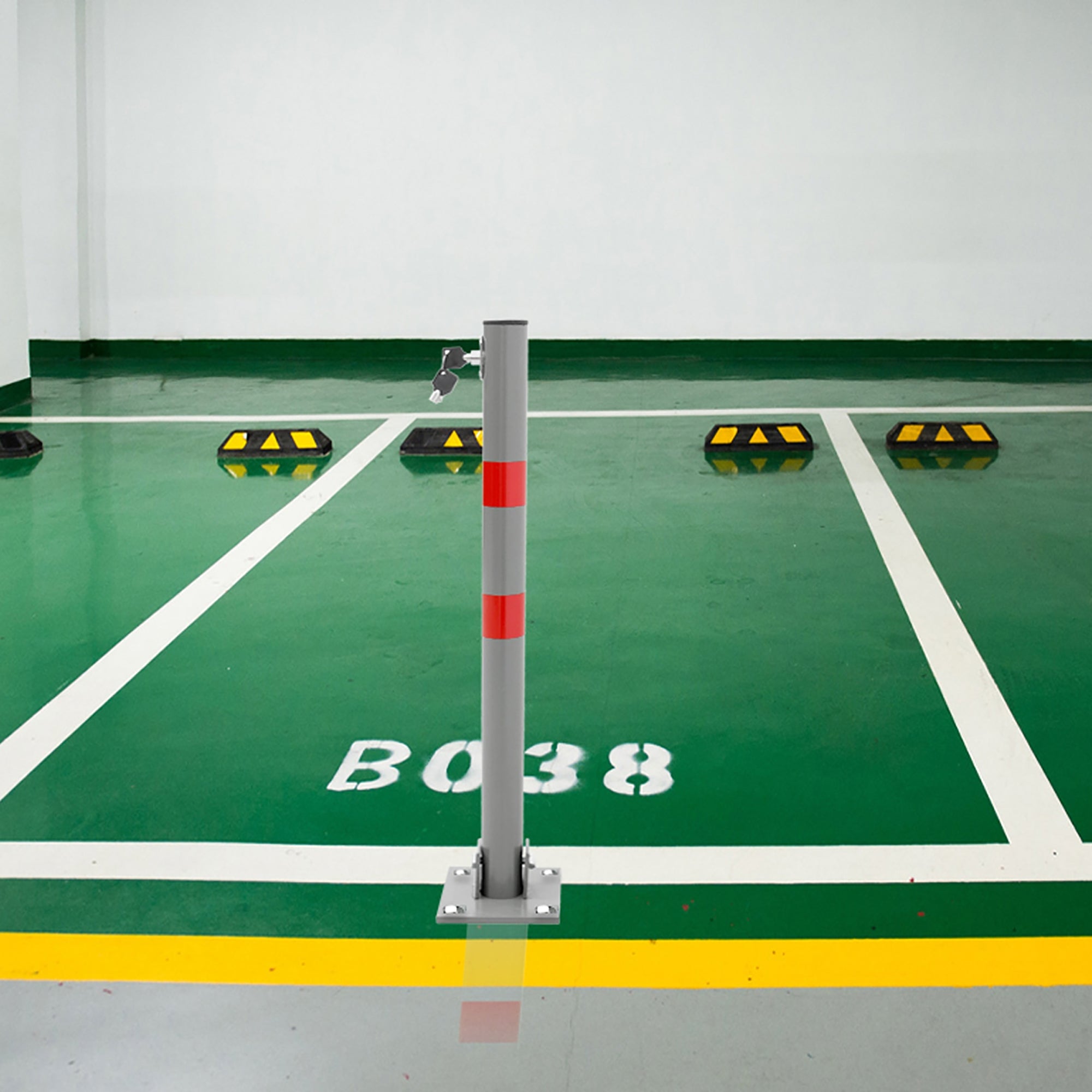 Parking avec un poteau gris et des marquages jaunes sur un sol vert.
