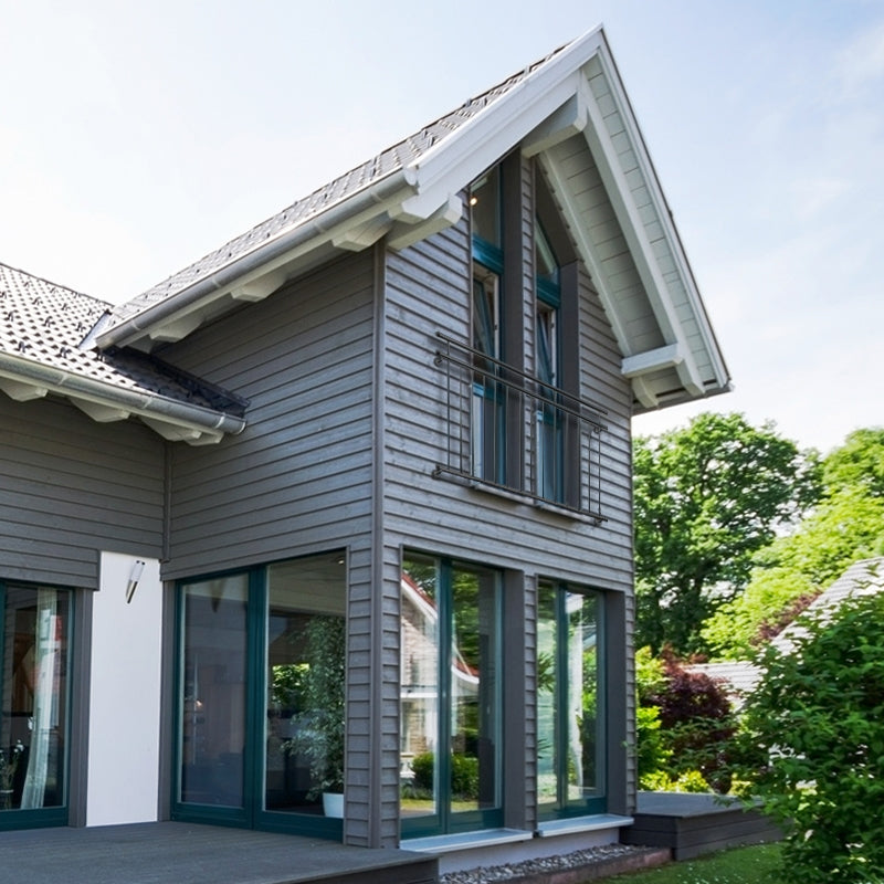 Haus mit schrägem Dach, großen Fenstern und Holzverkleidung.