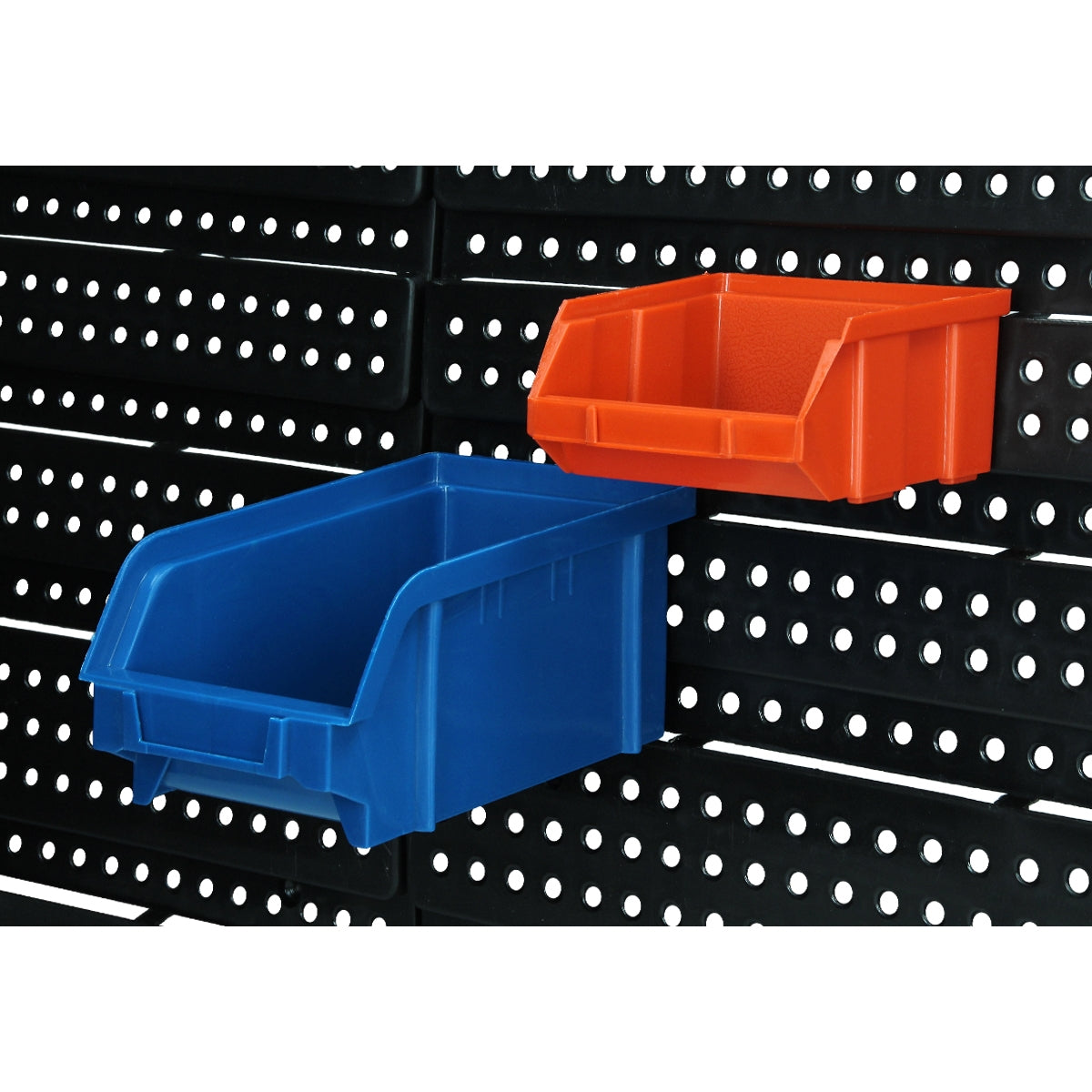 Blaue und orange Aufbewahrungsboxen an einer Lochwand.
