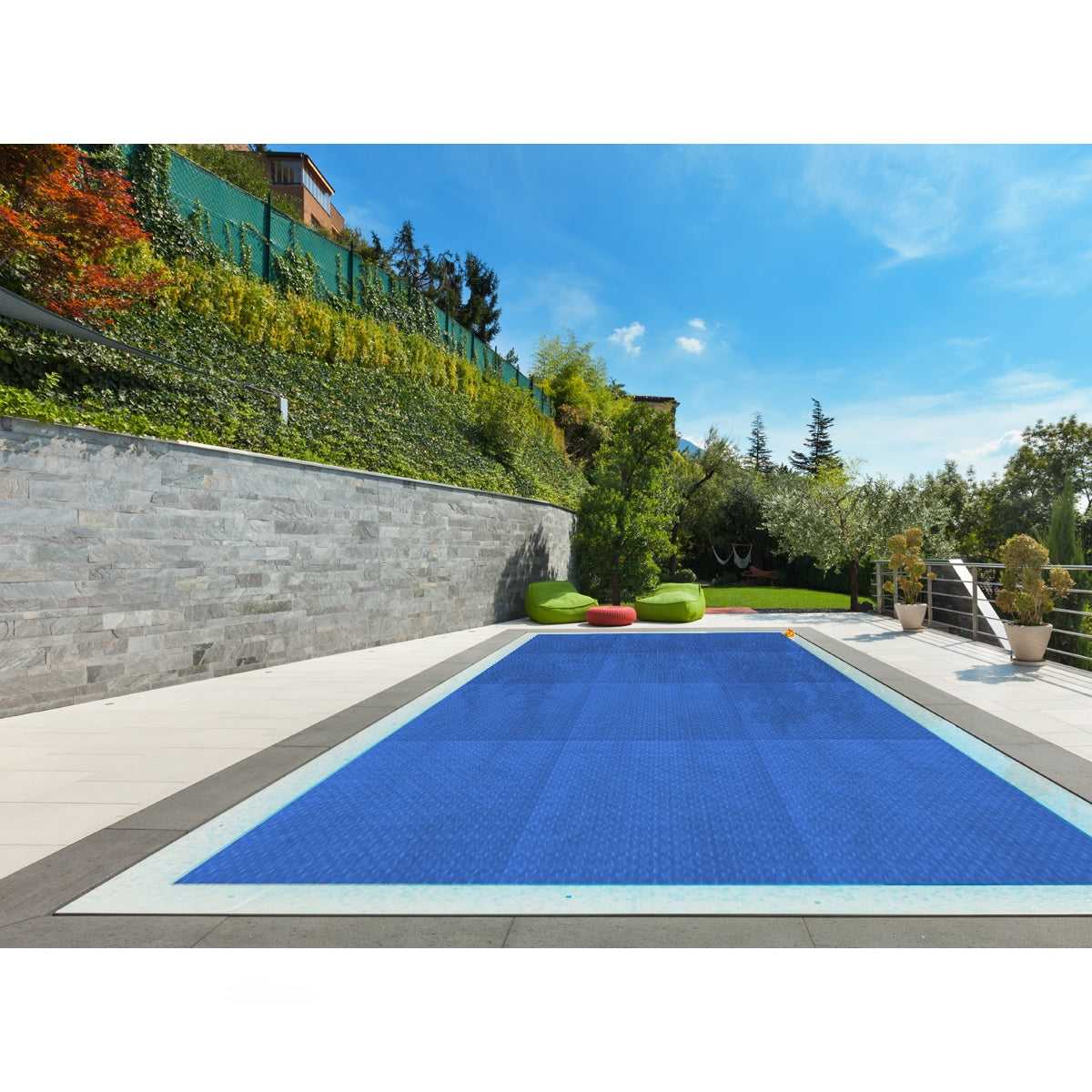 Una piscina azul con una cubierta, rodeada de plantas y muebles.