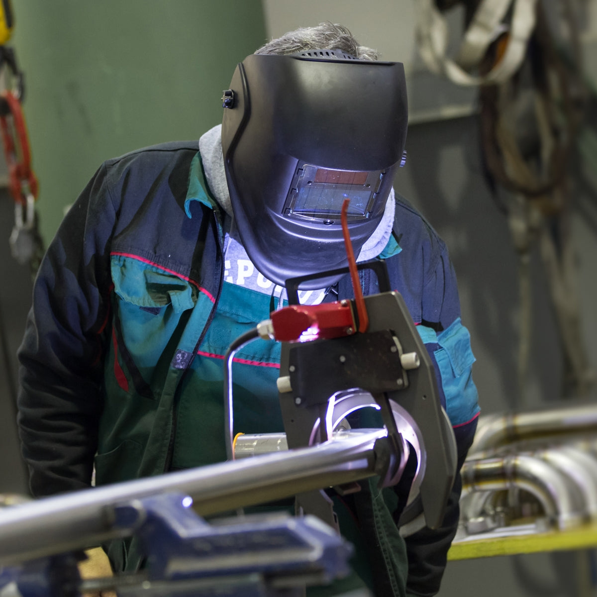 Un homme en tenue de travail soude avec un appareil de soudage.