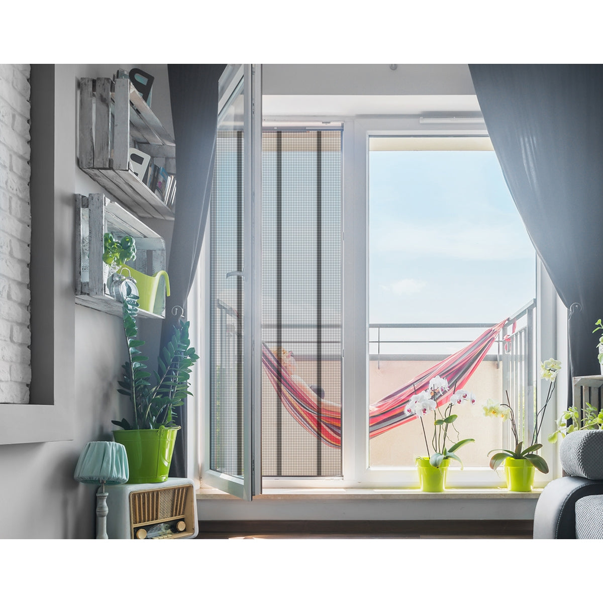 View of a balcony with a hammock and plants in front of an open window.