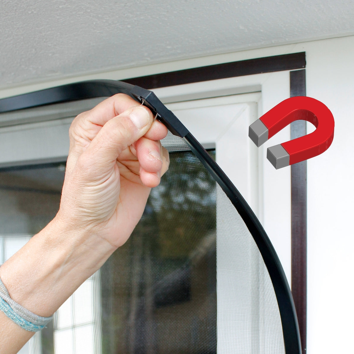 A hand holding a flexible frame with a magnet at a window.