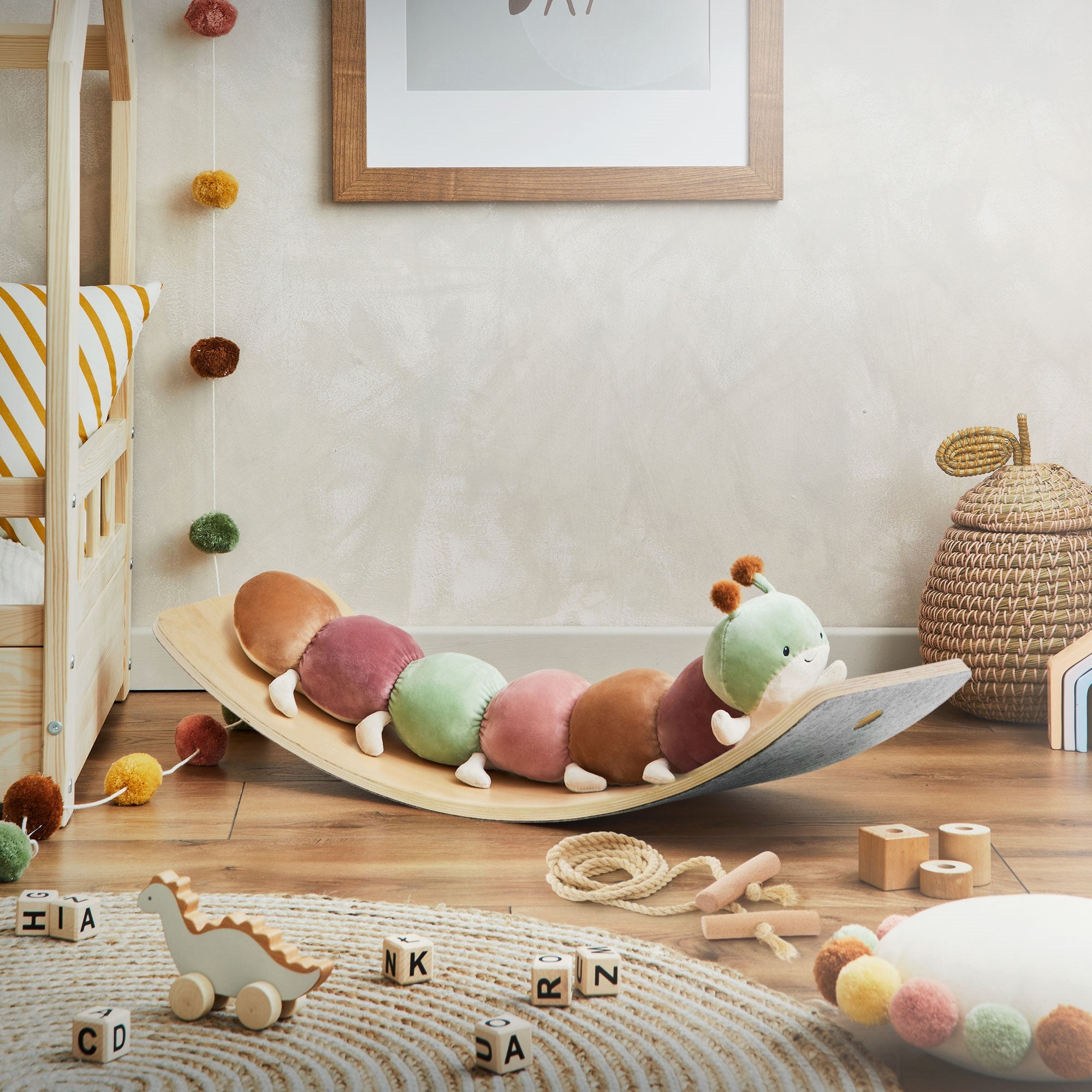 Bunte Spielzeugrutsche mit einer Raupe und Holzspielzeug im Raum.