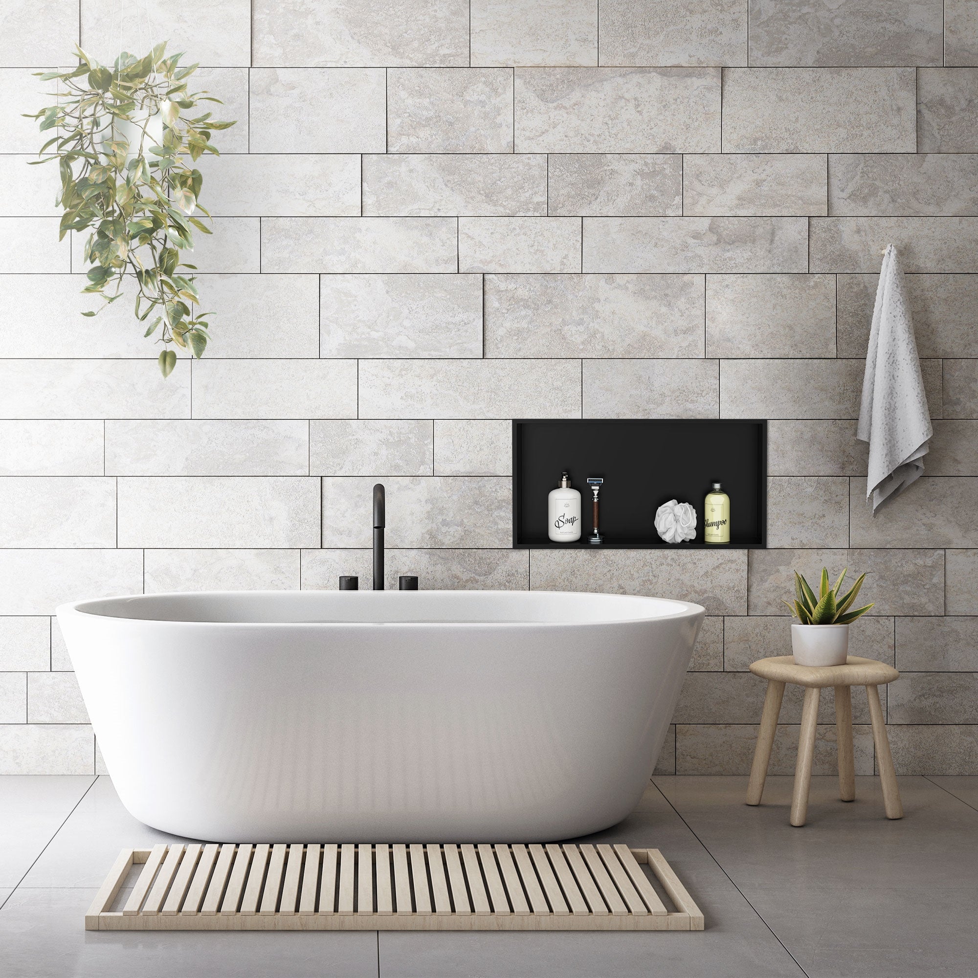 Freestanding bathtub in front of a stone wall with plants and toiletries.