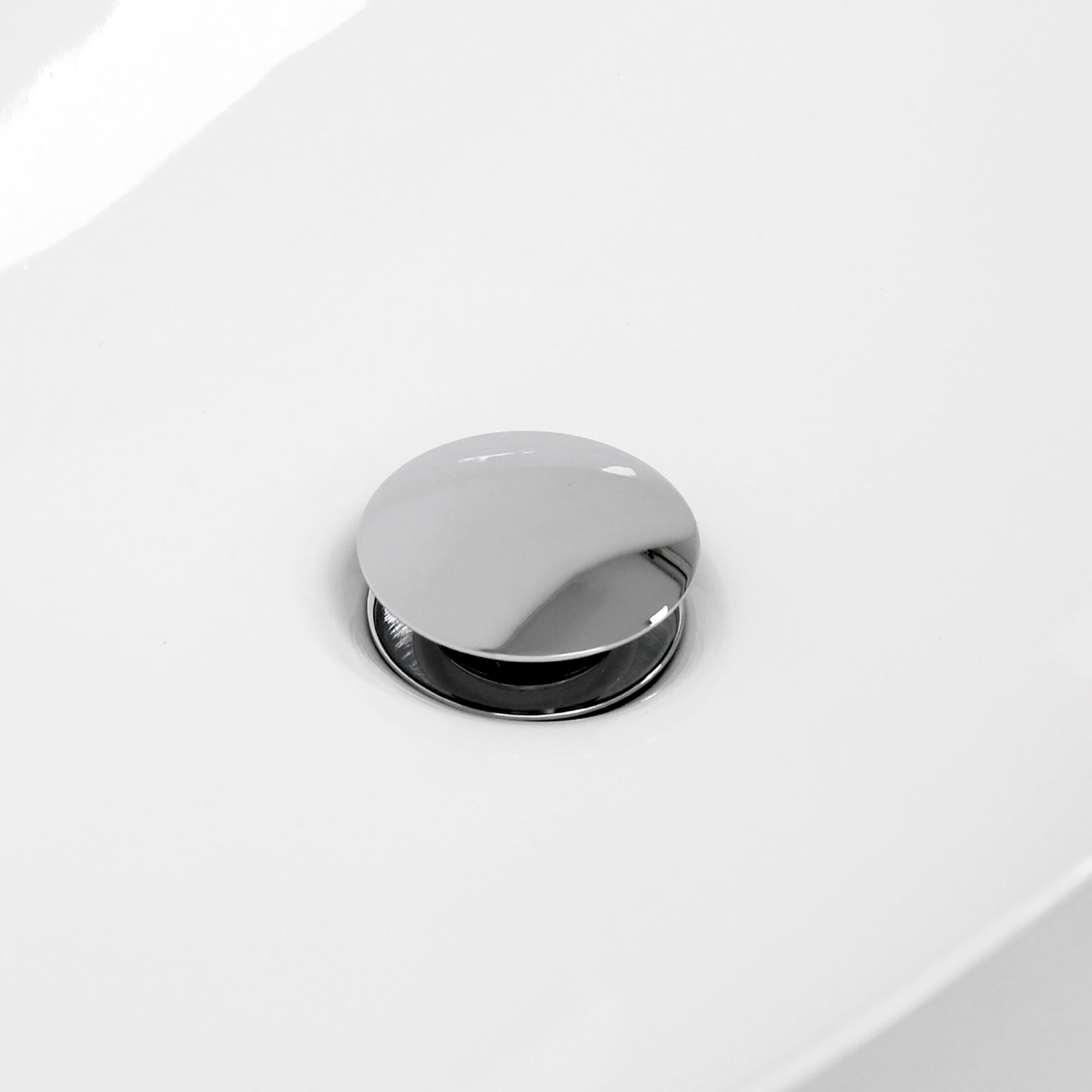 Close-up van een verchroomde afdekplug op een witte ondergrond.