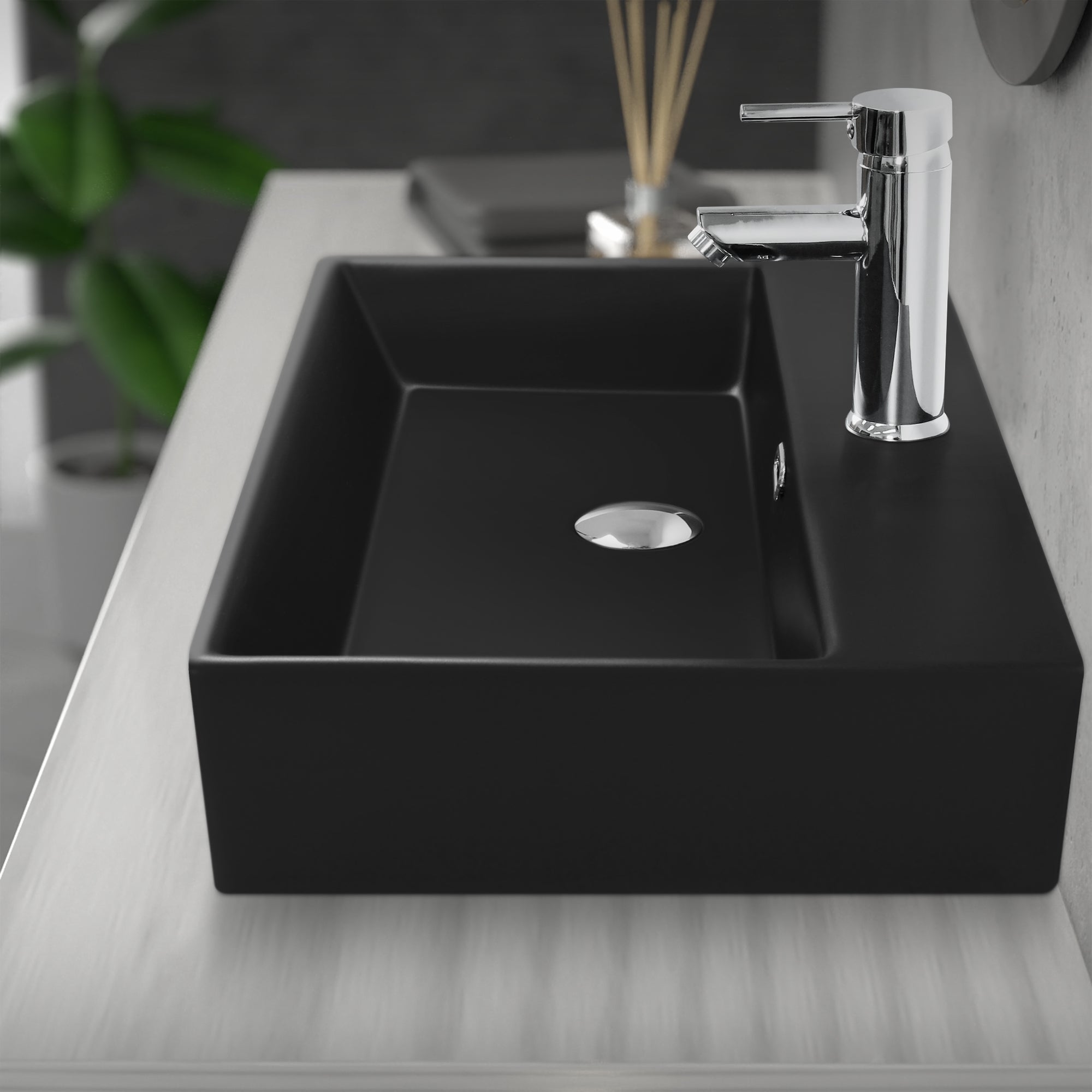 Lavabo noir sur une table, robinet et drain visibles.