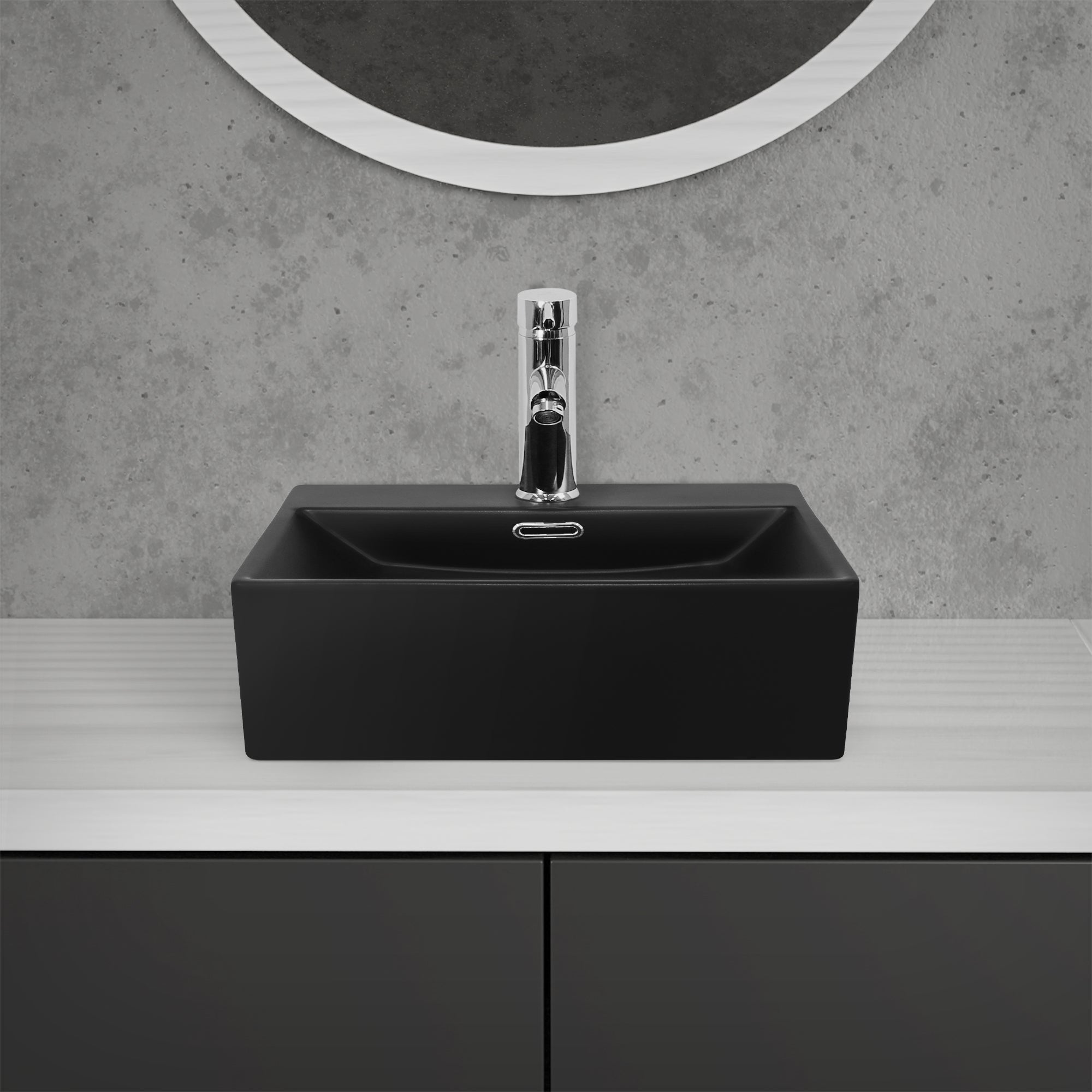 Black sink with faucet in front of a gray wall.
