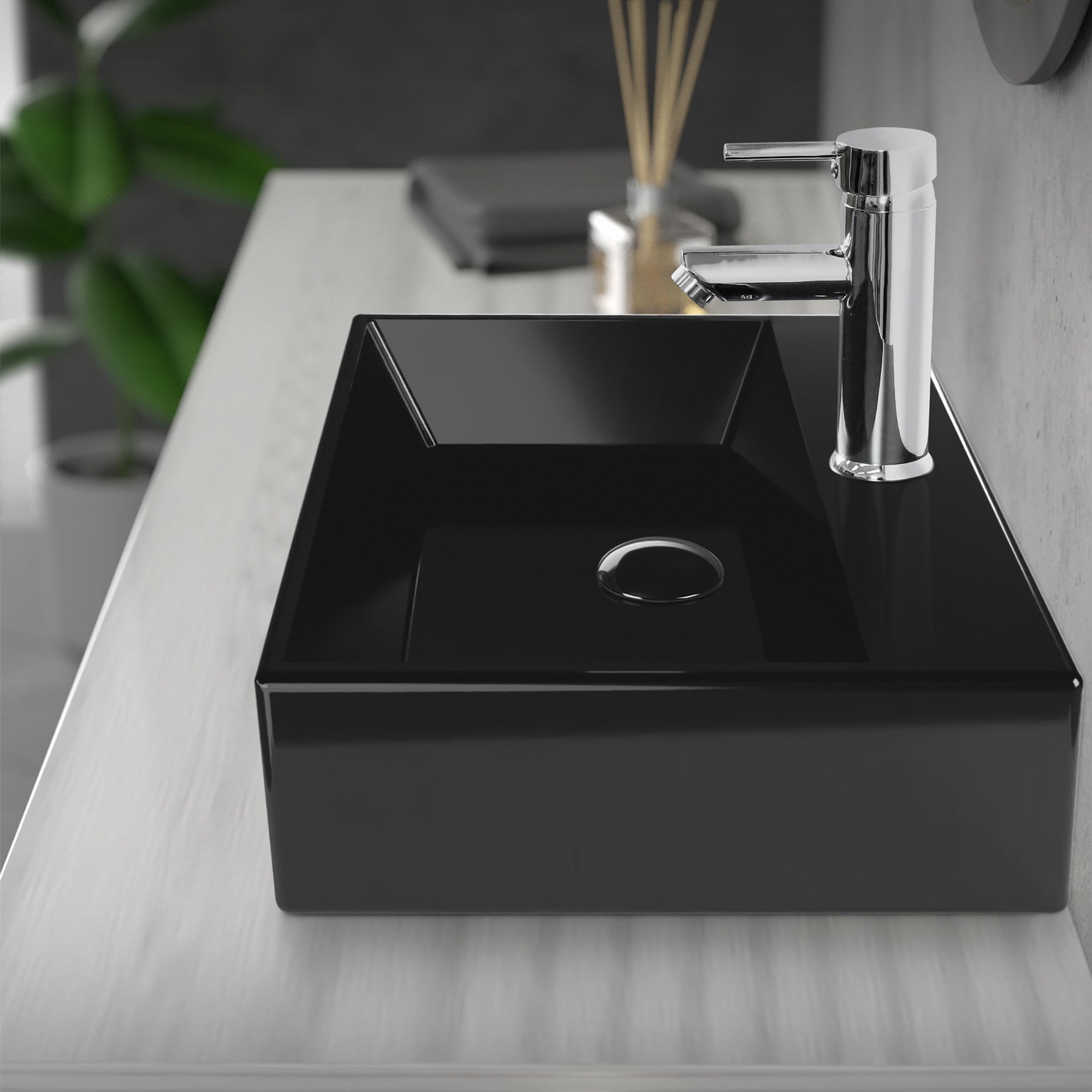Schwarzes Waschbecken mit Wasserhahn auf einem hellen Tisch.